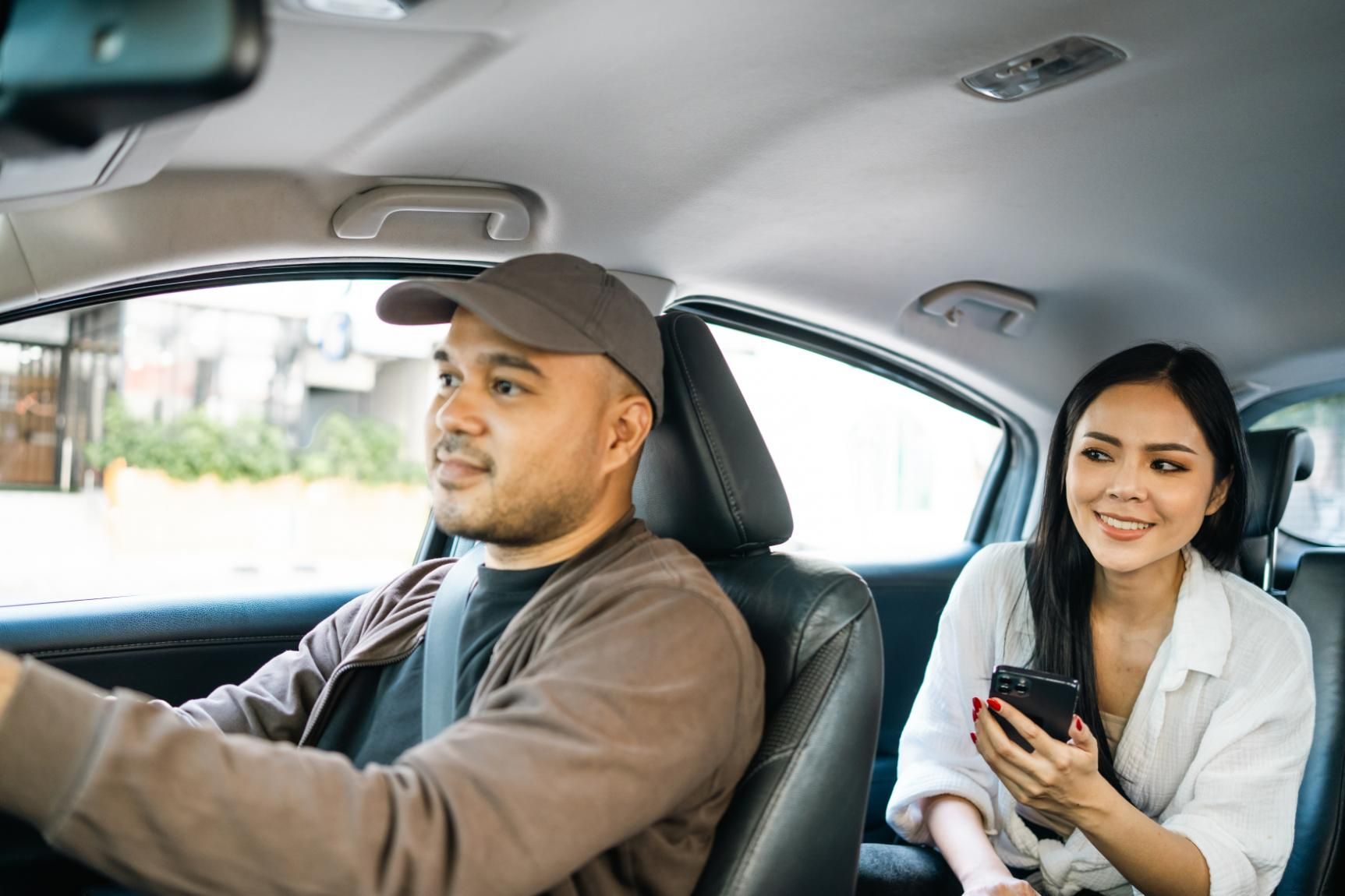 A Man Is Driving a Car with A Woman Sitting in The Back Seat — Greenaway's Taxi in Nabiac, NSW
