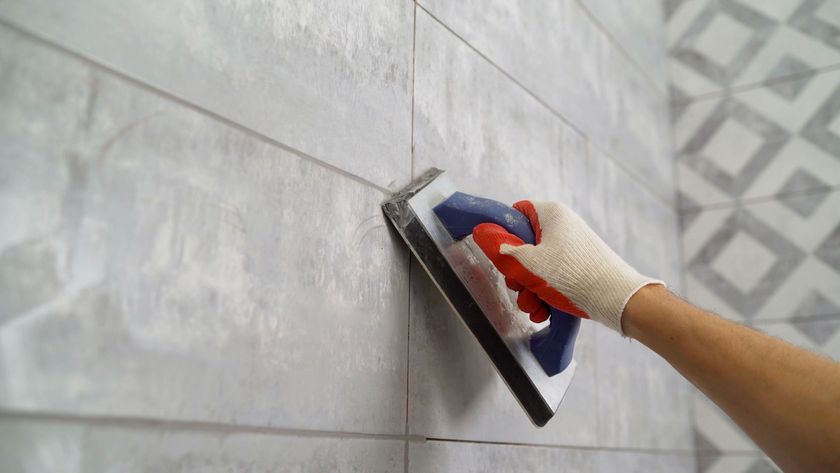 A person is using a sponge to grout a tile wall.