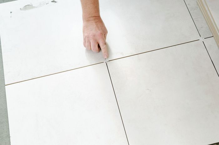 A person is laying tiles on a floor.