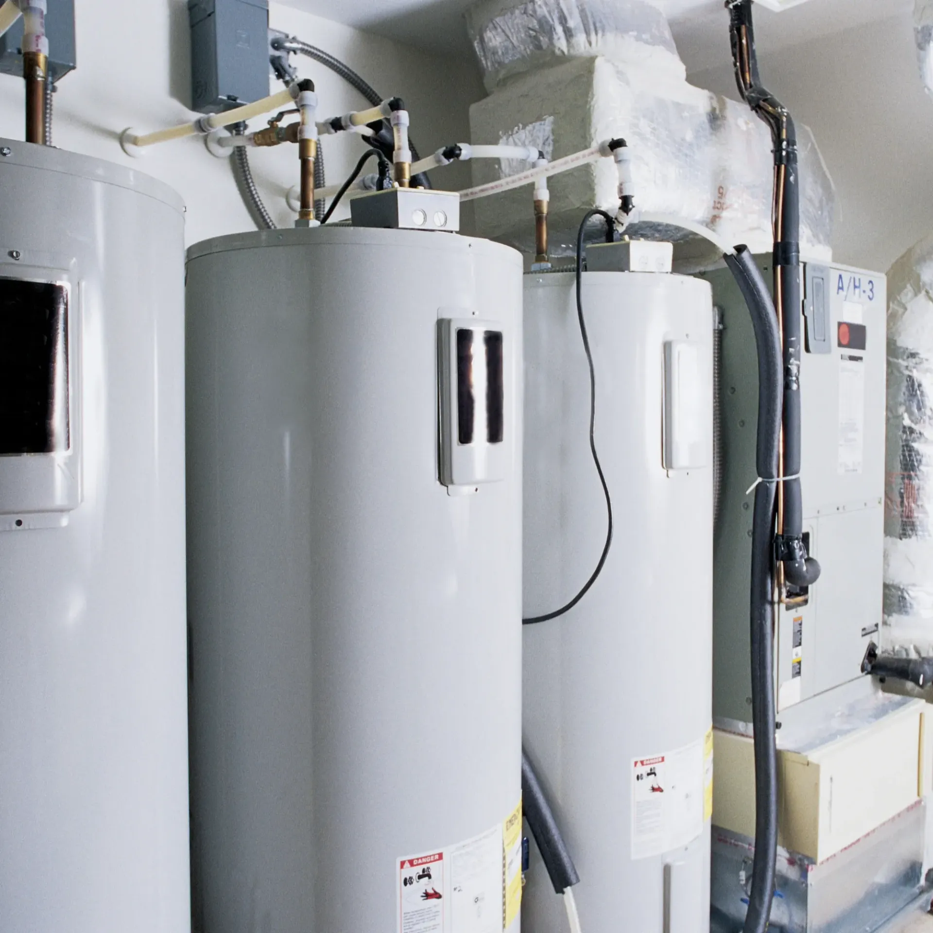 Aarden Air Service Heating & Air Conditioning- Three white water heaters are lined up in a room