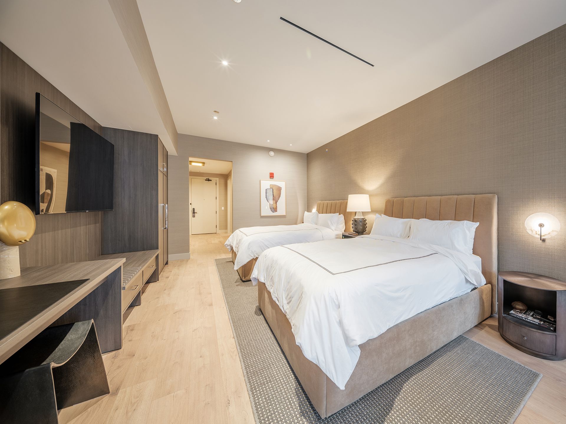 A hotel room with two beds , a desk and a television.