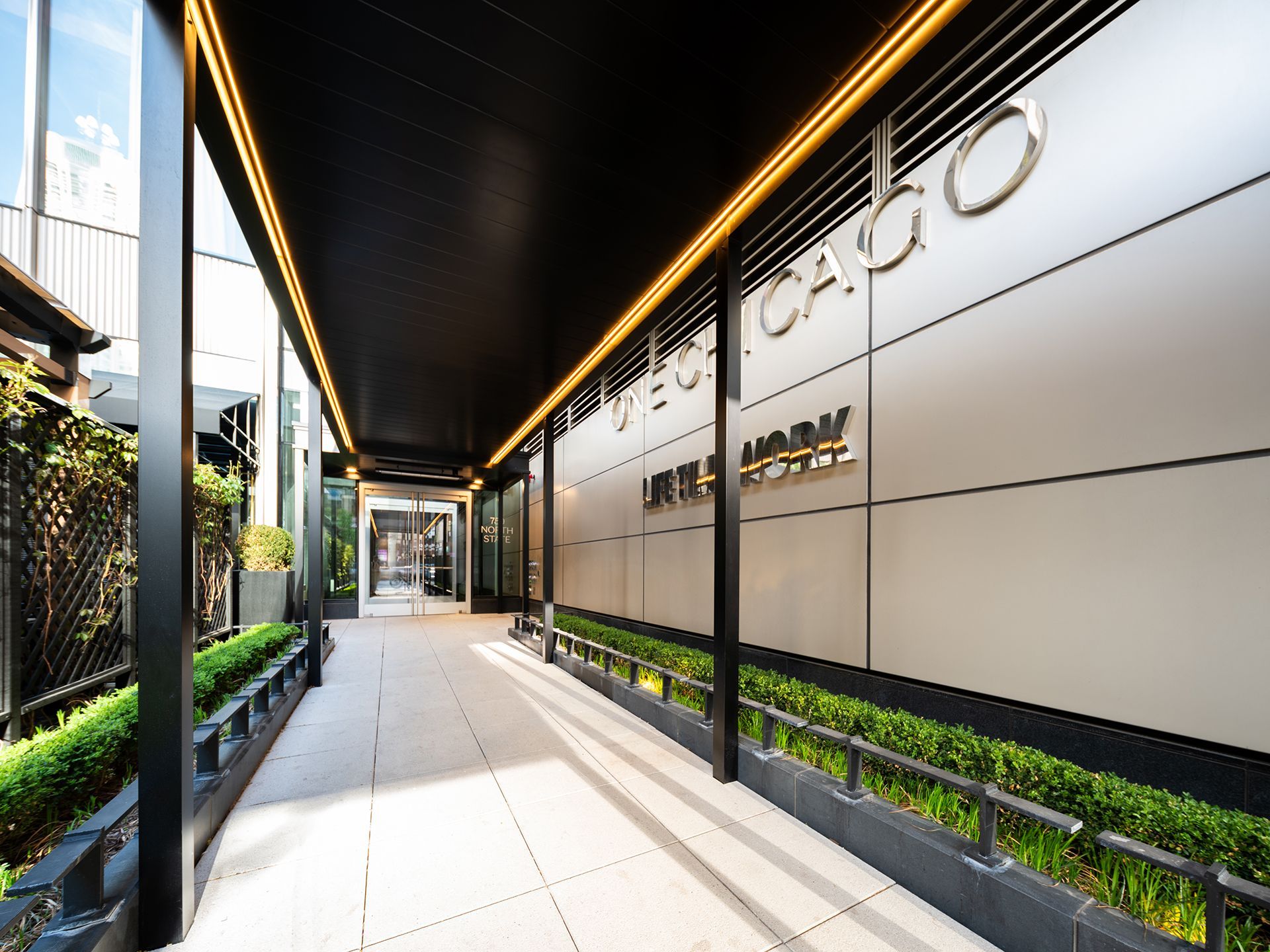 A modern exterior walkway with the hotel name 'Stay One Chicago' on the wall.