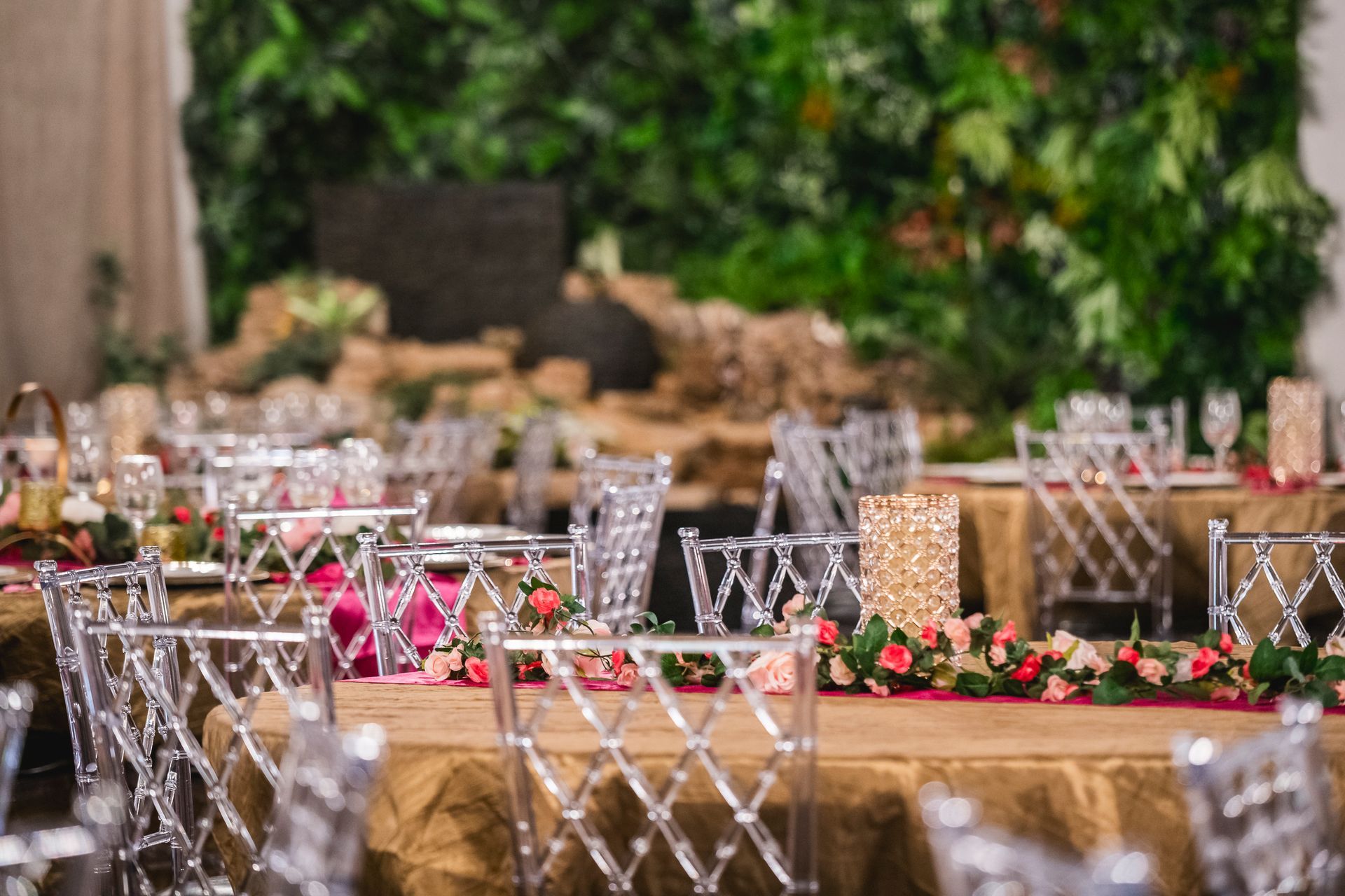 Set tables with crystal chairs and pink floral centerpieces at an outdoor event venue
