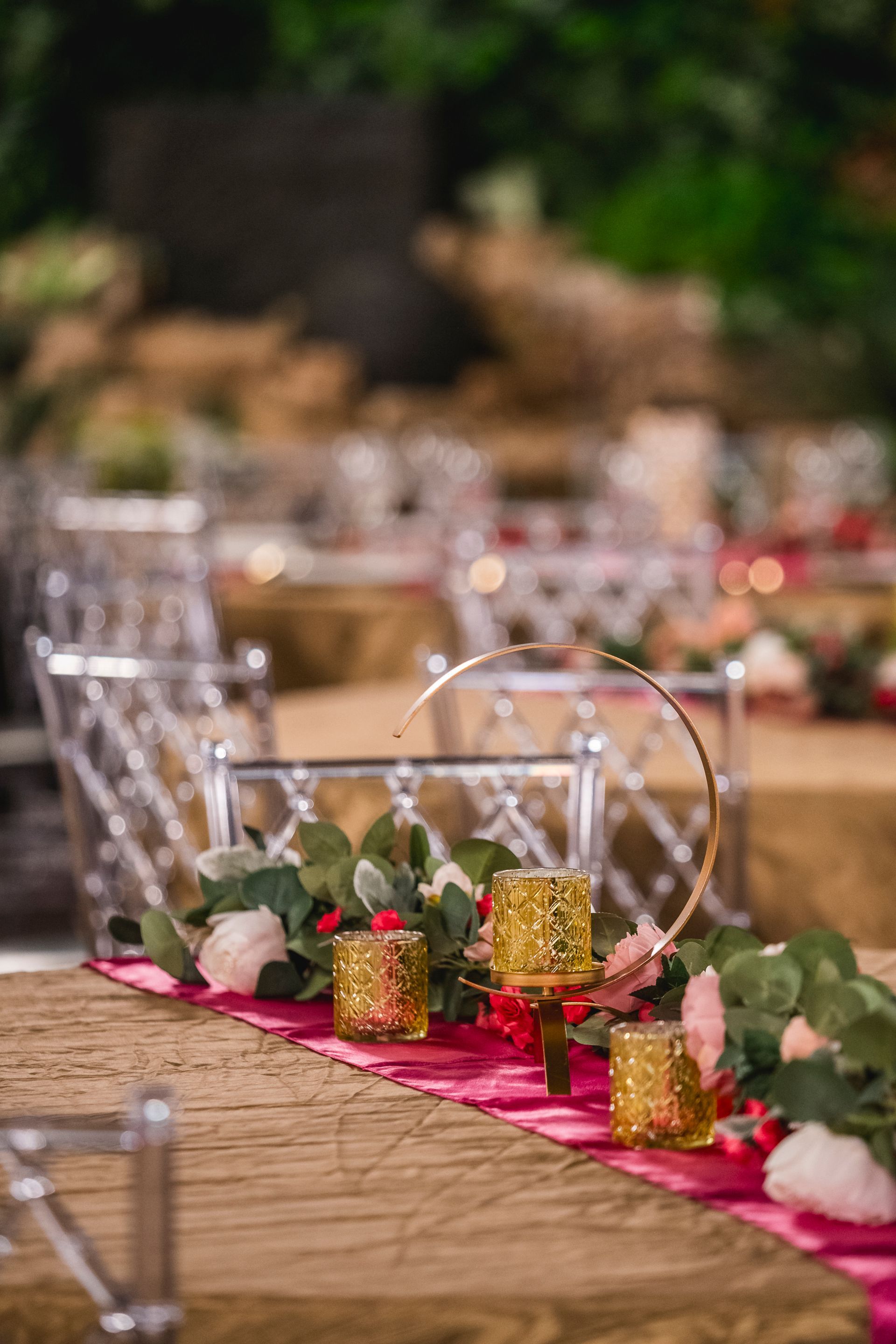 Decorated banquet table with pink runner, candles, greenery, and floral centerpieces