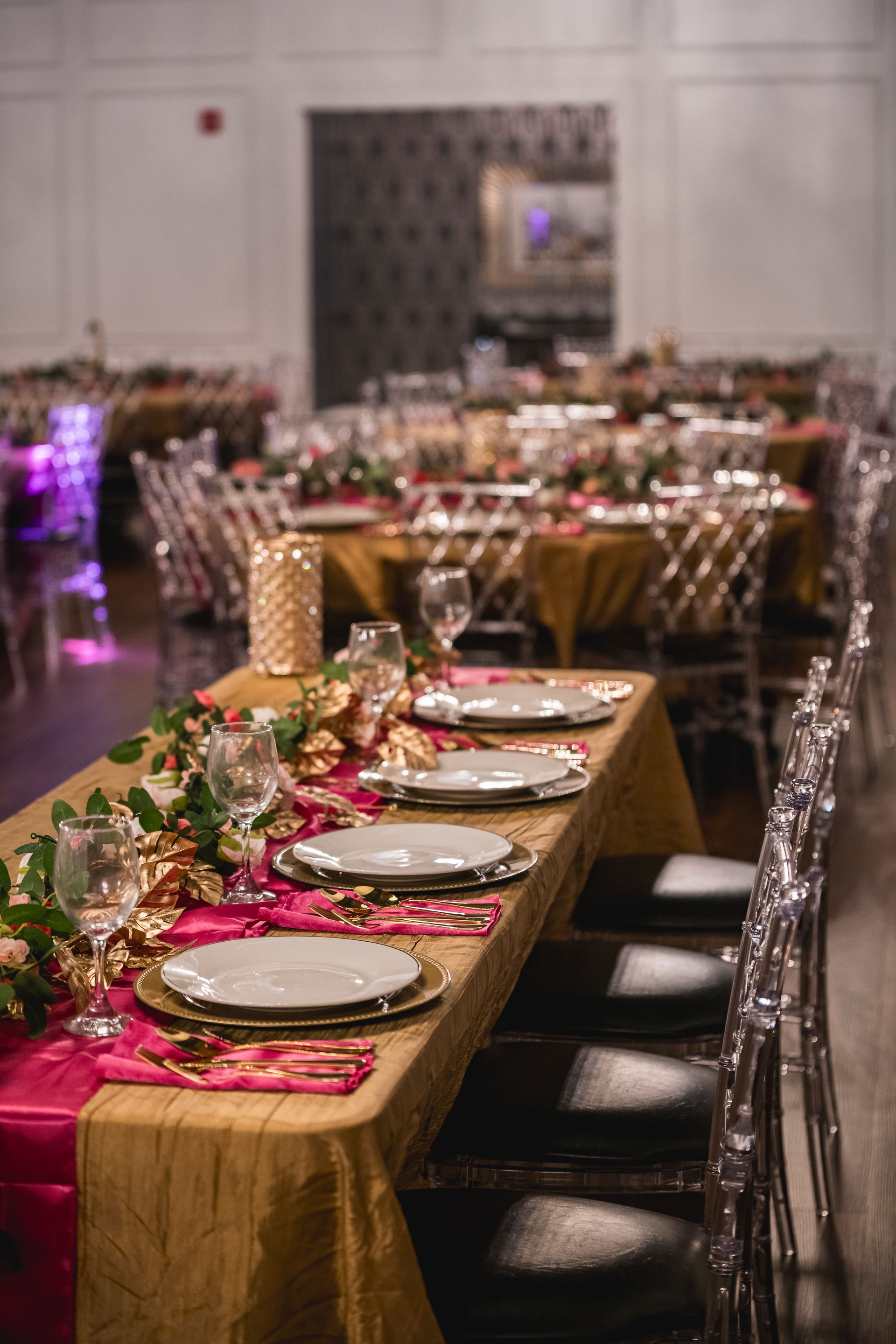Elegant banquet table with gold and red decor, set for a formal event in a large reception hall
