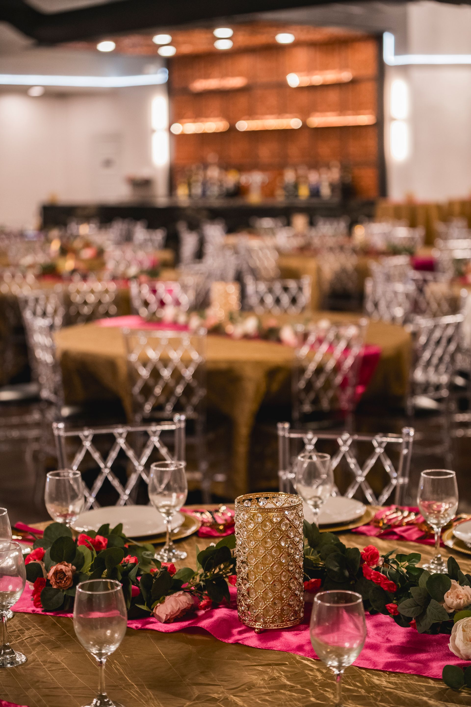 Elegant banquet hall with round tables, gold tablecloths, floral centerpieces, and wine glasses set for an event