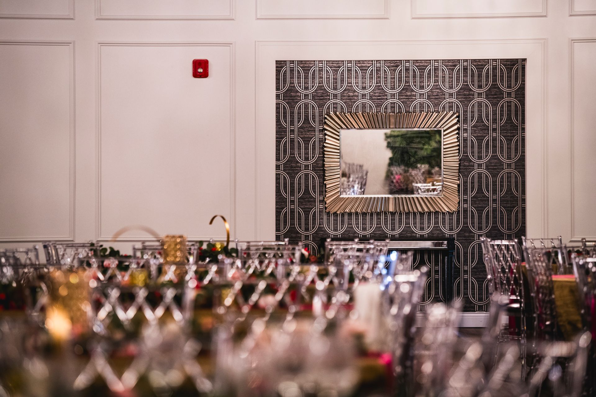 Elegant event hall with a mirrored wall, white paneling, and blurred tables set for a banquet