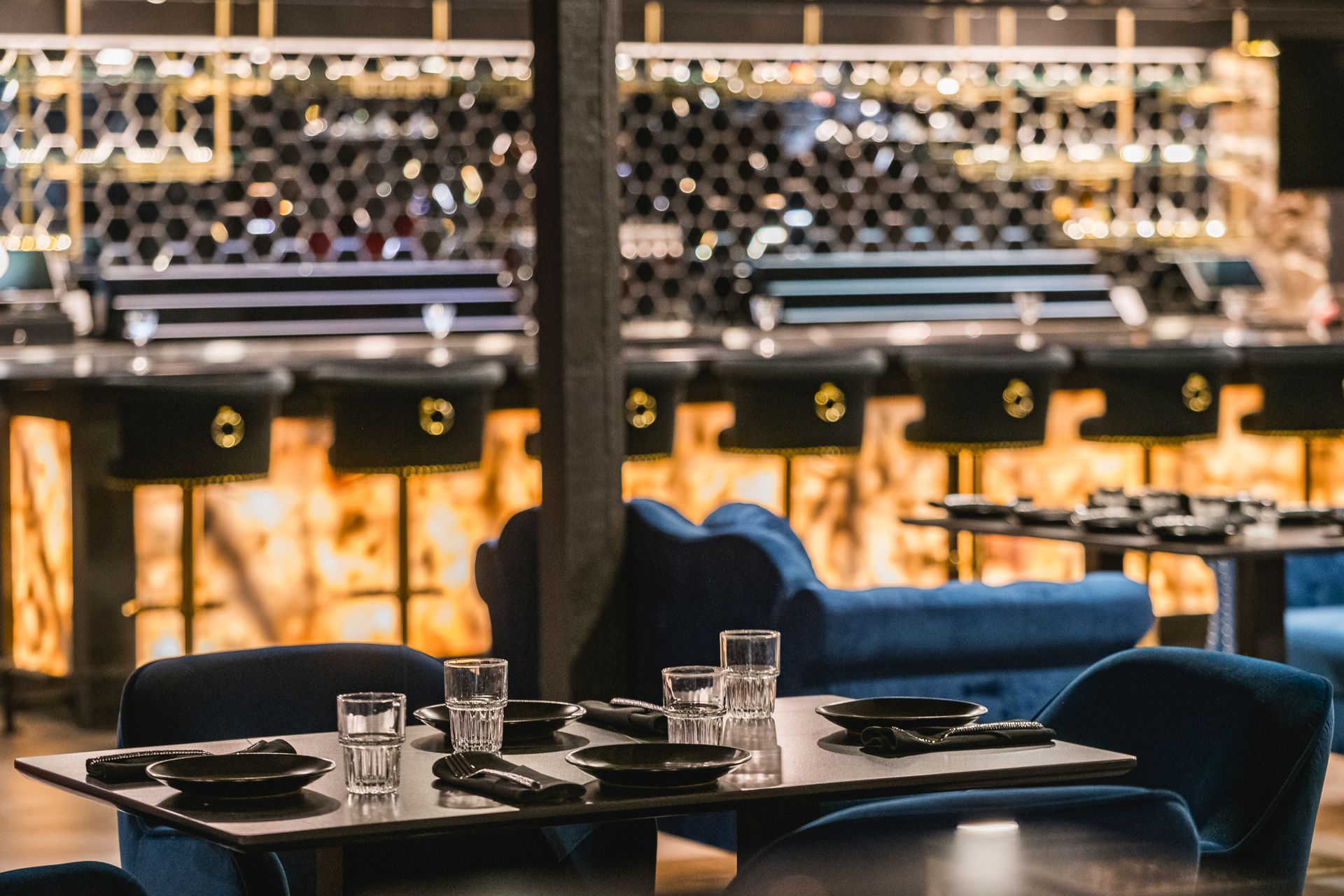 Elegant restaurant dining area with set tables, blue chairs, and warm ambient lighting