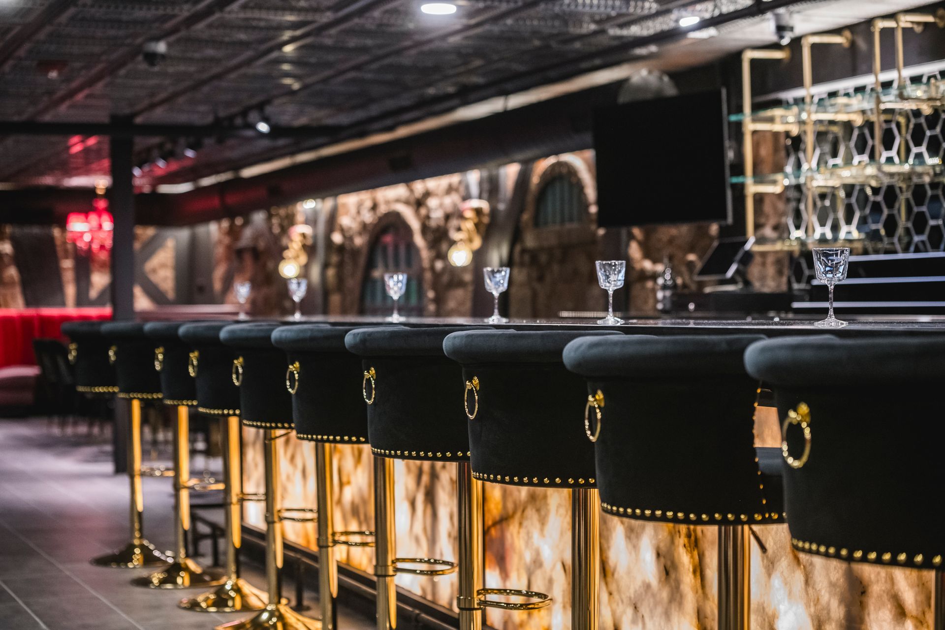 Empty bar with black stools and warm under-counter lighting in a modern lounge