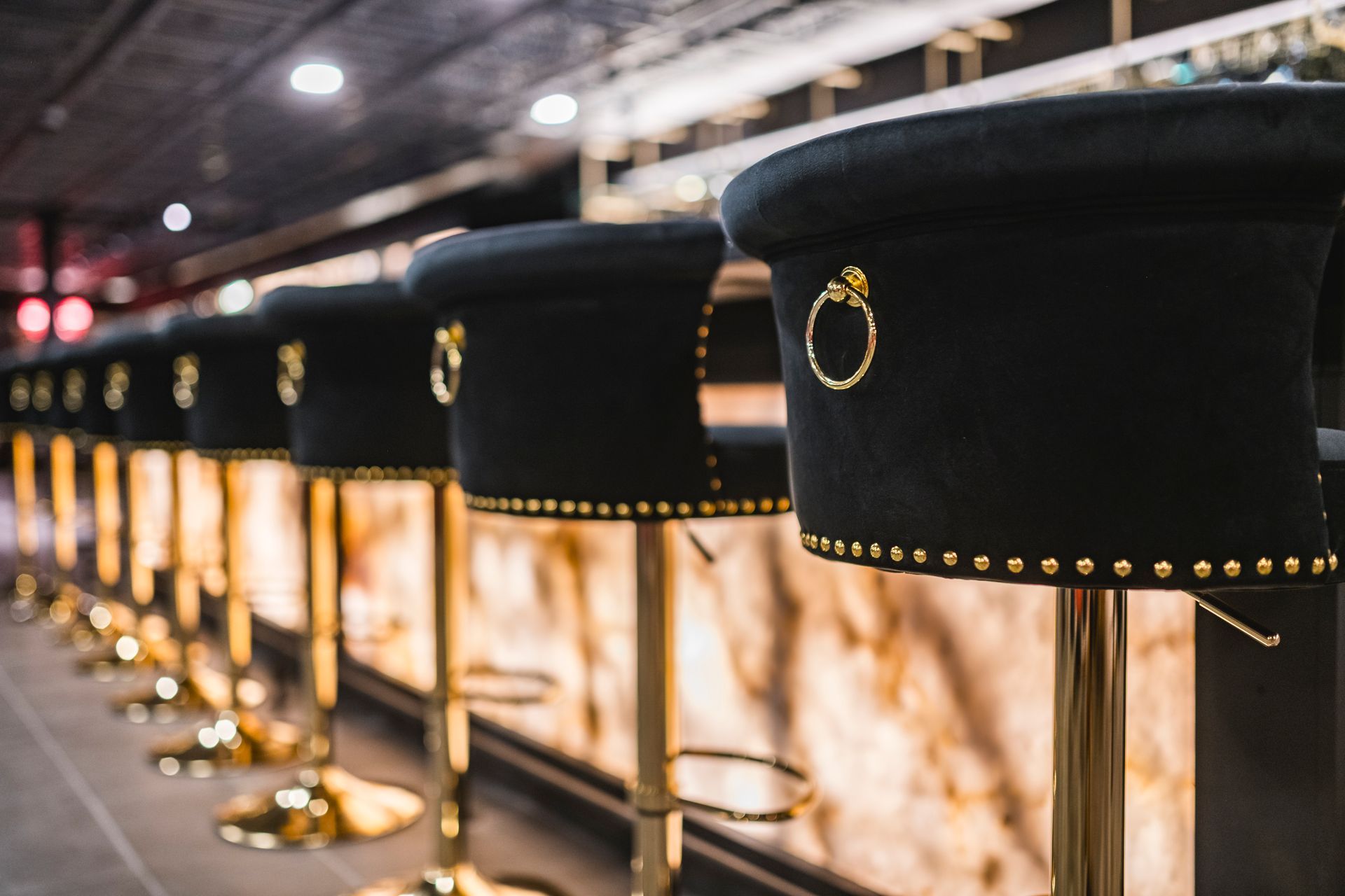 Black velvet stanchions with gold studs line a warmly lit indoor walkway.