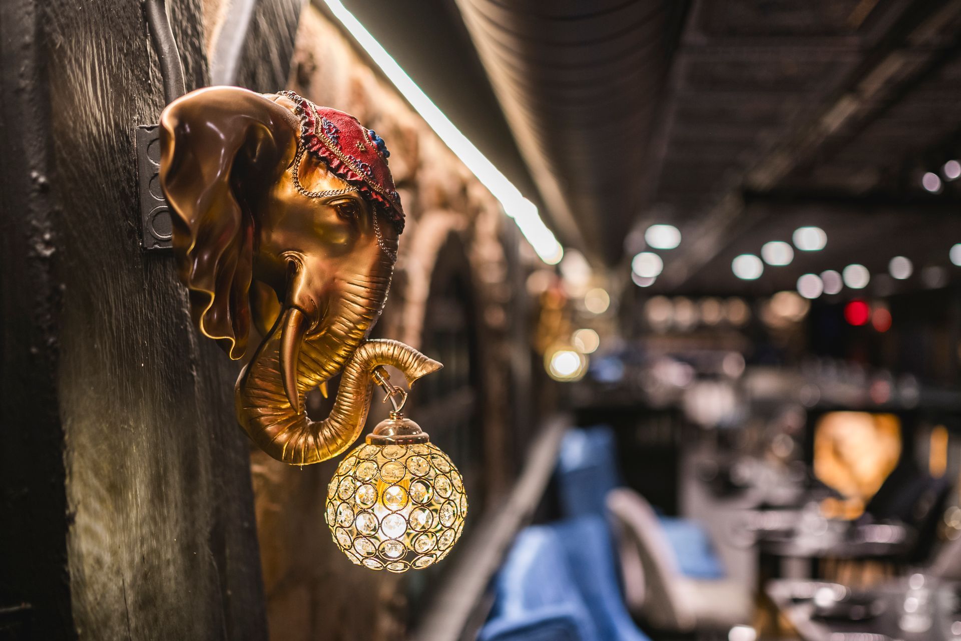 Golden elephant wall lamp with hanging crystal orb in a softly lit interior.