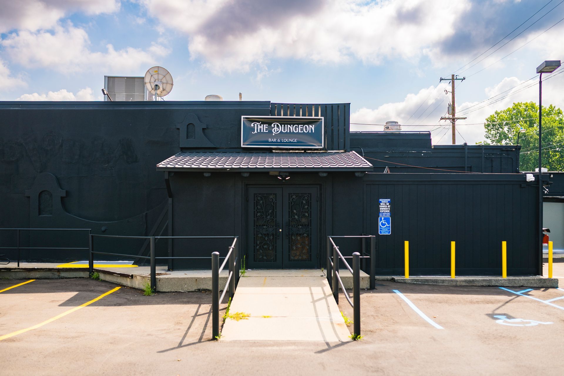 Dark storefront with a ramp entrance and parking spaces in front