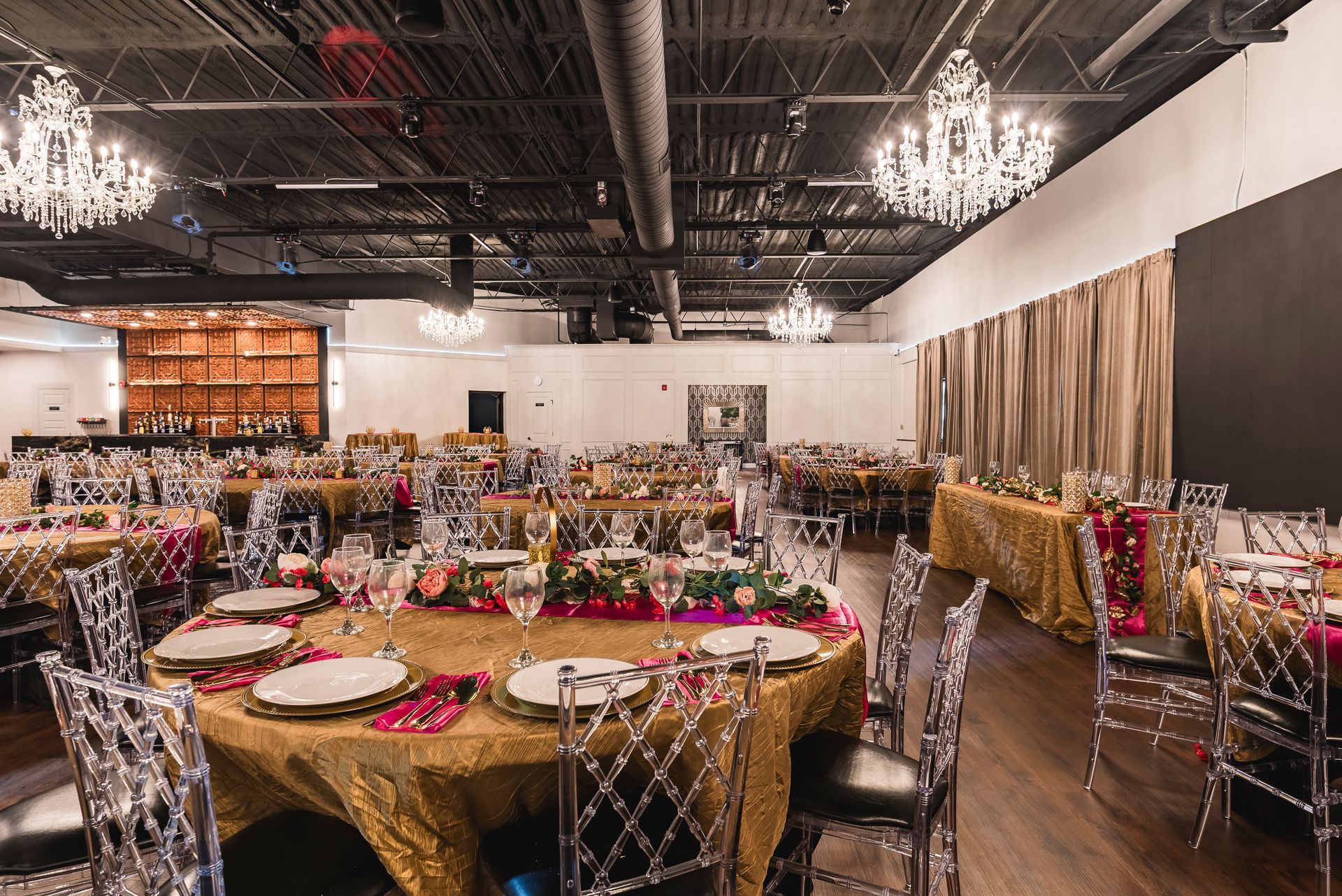 Banquet hall with round tables, floral centerpieces, and clear chairs set for an event