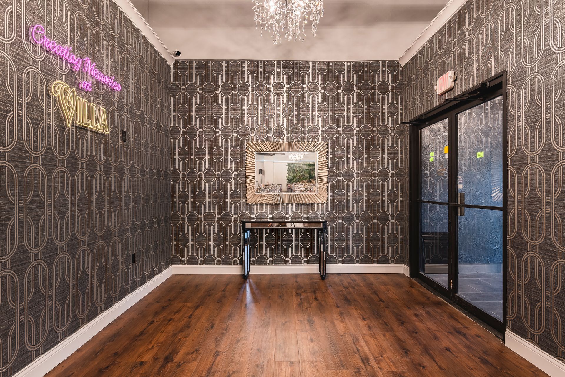 Empty modern room with dark patterned wallpaper, wood floor, table, and glass double doors