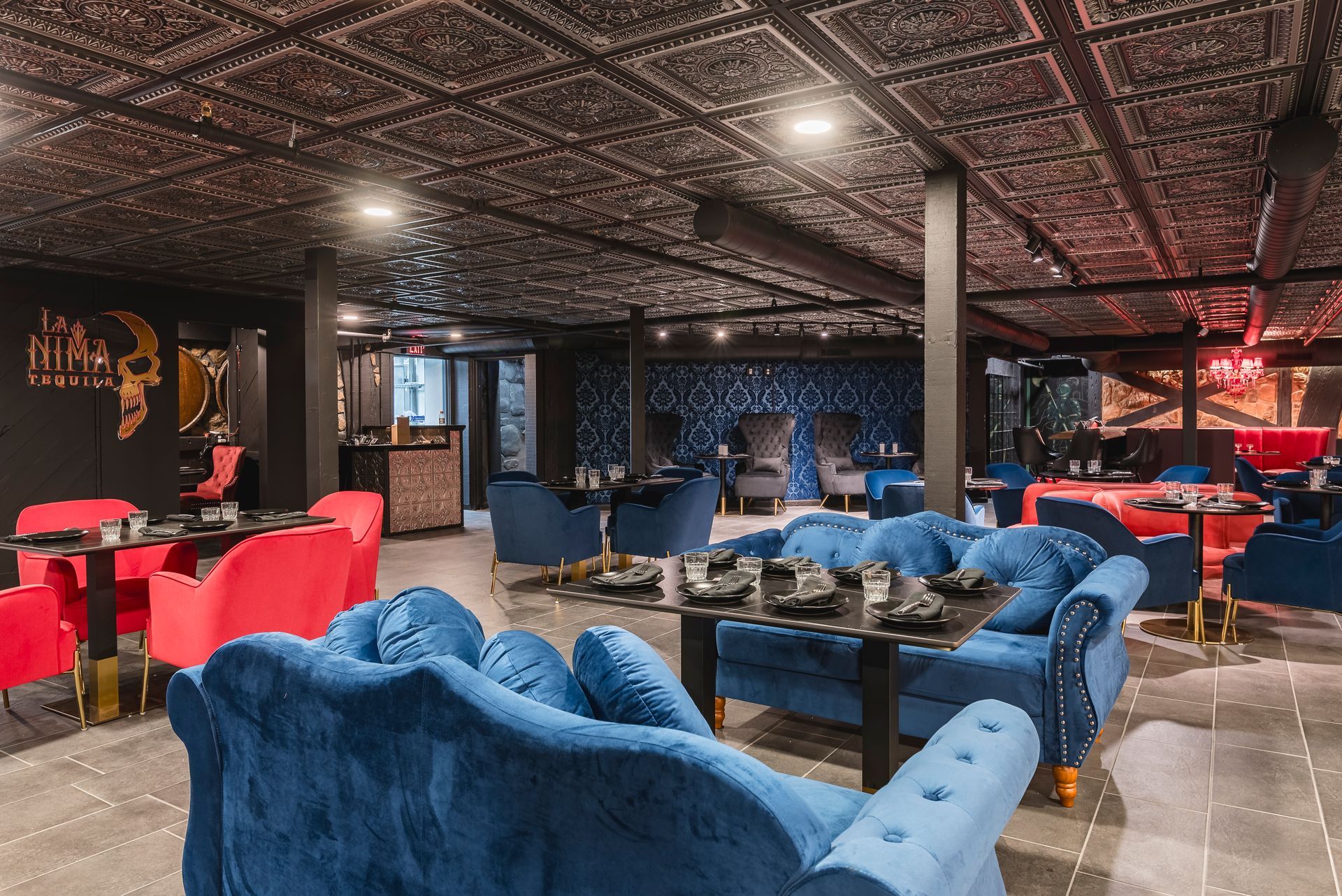 Colorful lounge with blue and red sofas, patterned ceiling, and warm lighting in a modern interior.
