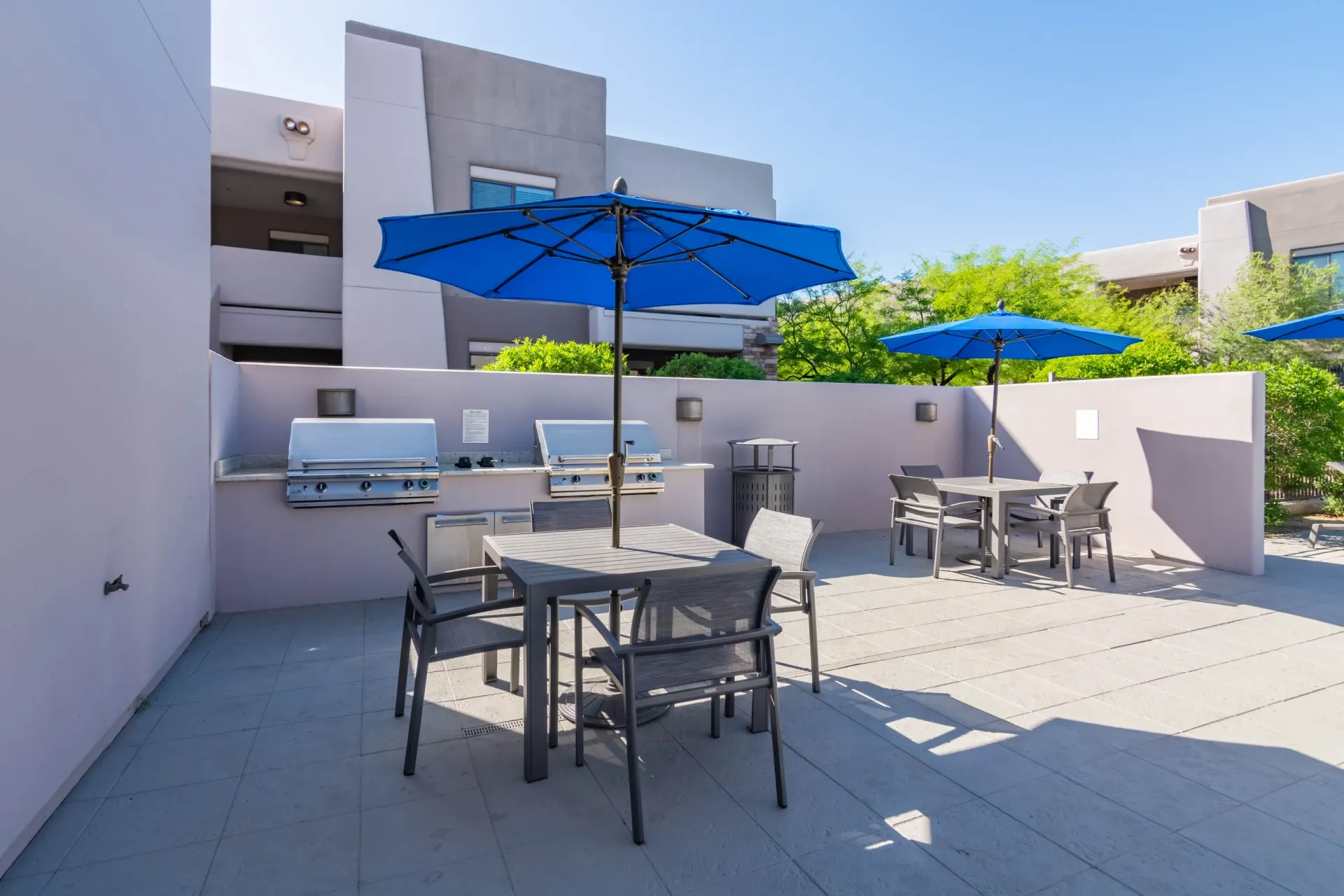 Outdoor grilling area with two built-in grills, tables, and umbrellas.