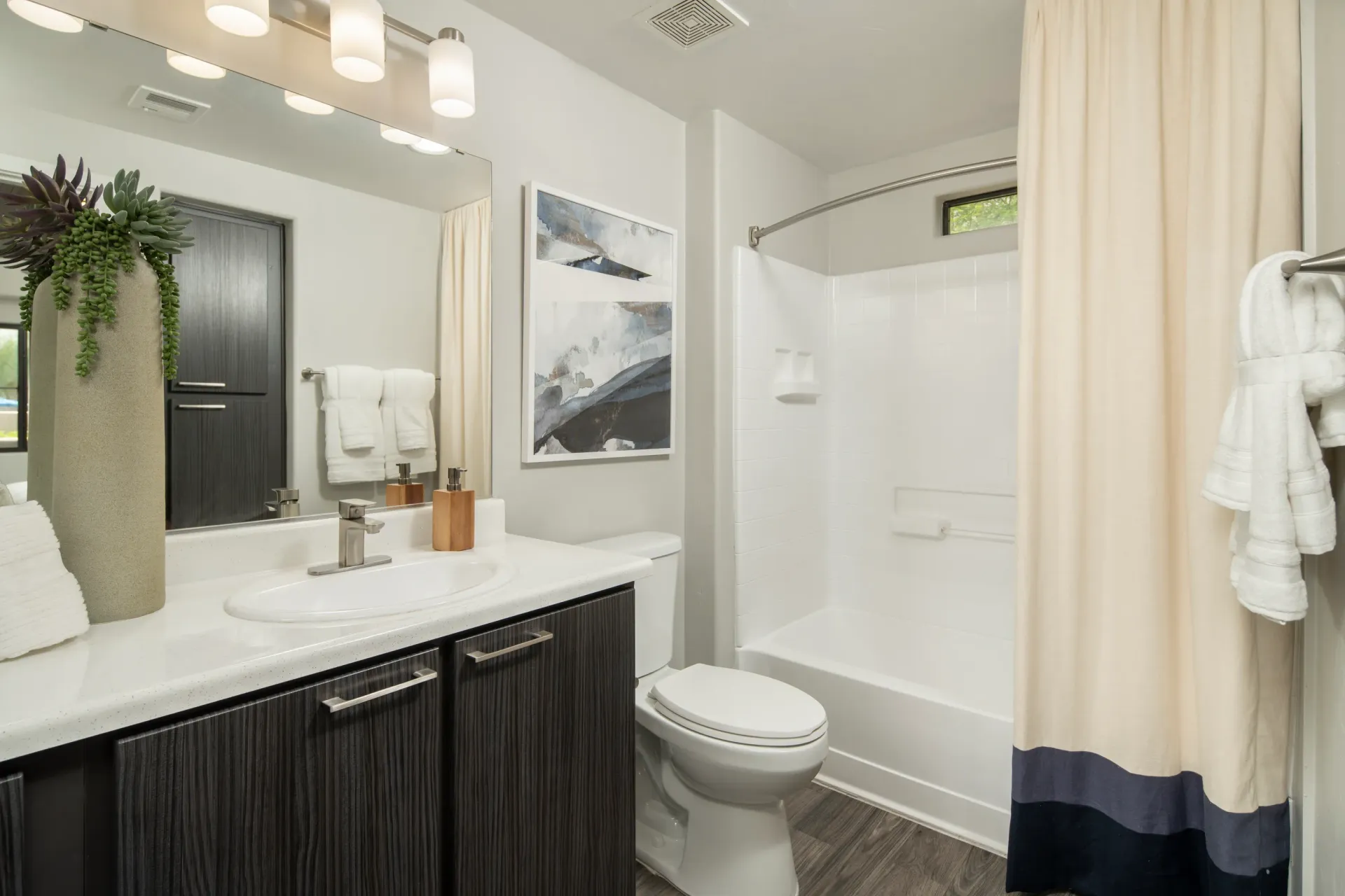 Modern bathroom with a vanity, toilet, and shower/tub combo.