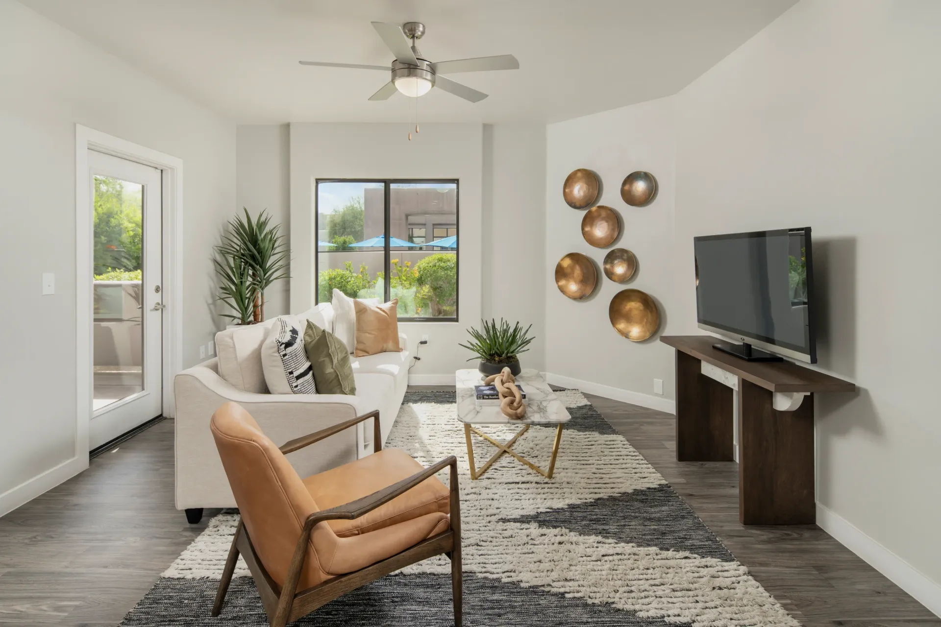 Living room with a white sofa, leather accent chair, marble coffee table, and a TV.