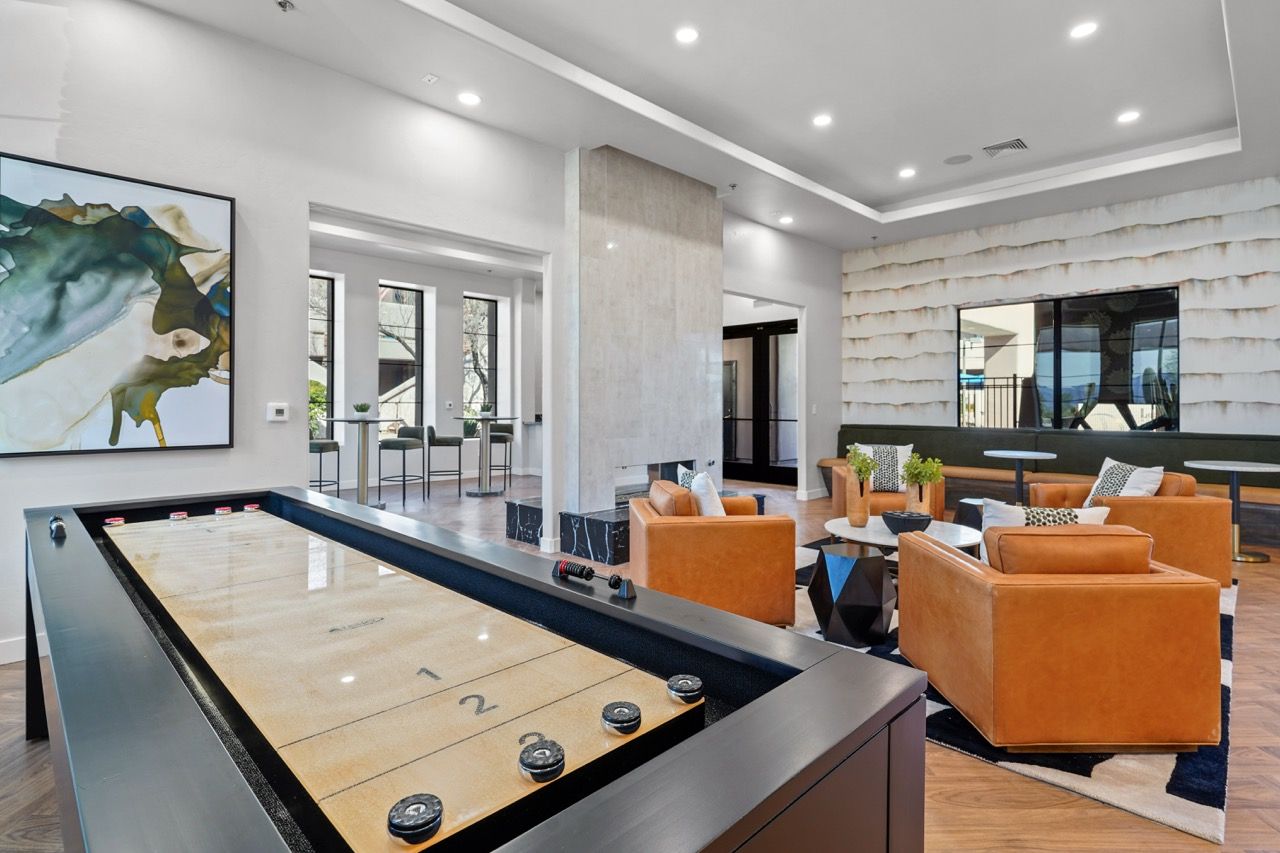 Modern communal lounge with a large pool table and tan leather seating under bright lights at Legacy Apartments at Dove Mountain in Marana, AZ.
