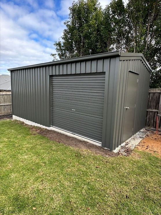 Exterior view of a secure, dark corrugated metal storage shed with a large roller door, representing reliable Storage Warrnambool and professional Storage Services Warrnambool. Exterior view of a secure, dark corrugated metal storage shed with a large roller door, representing reliable Storage Warrnambool and professional Storage Services Warrnambool.
