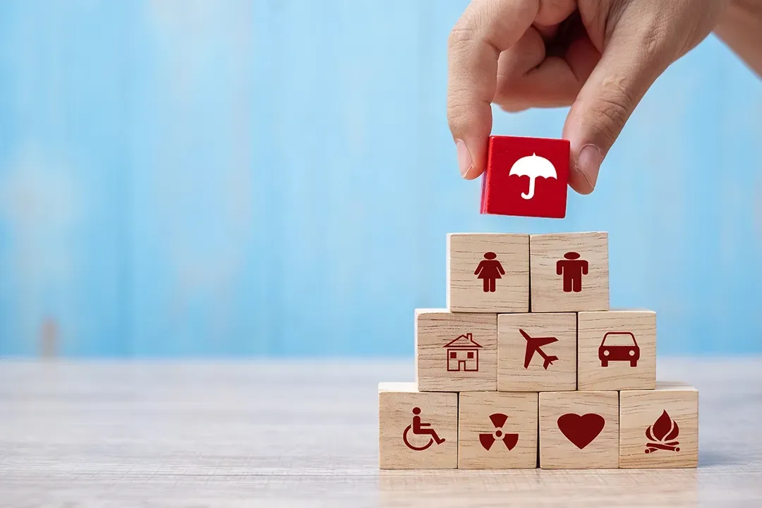A person is putting a red block with an umbrella on top of a stack of wooden blocks.