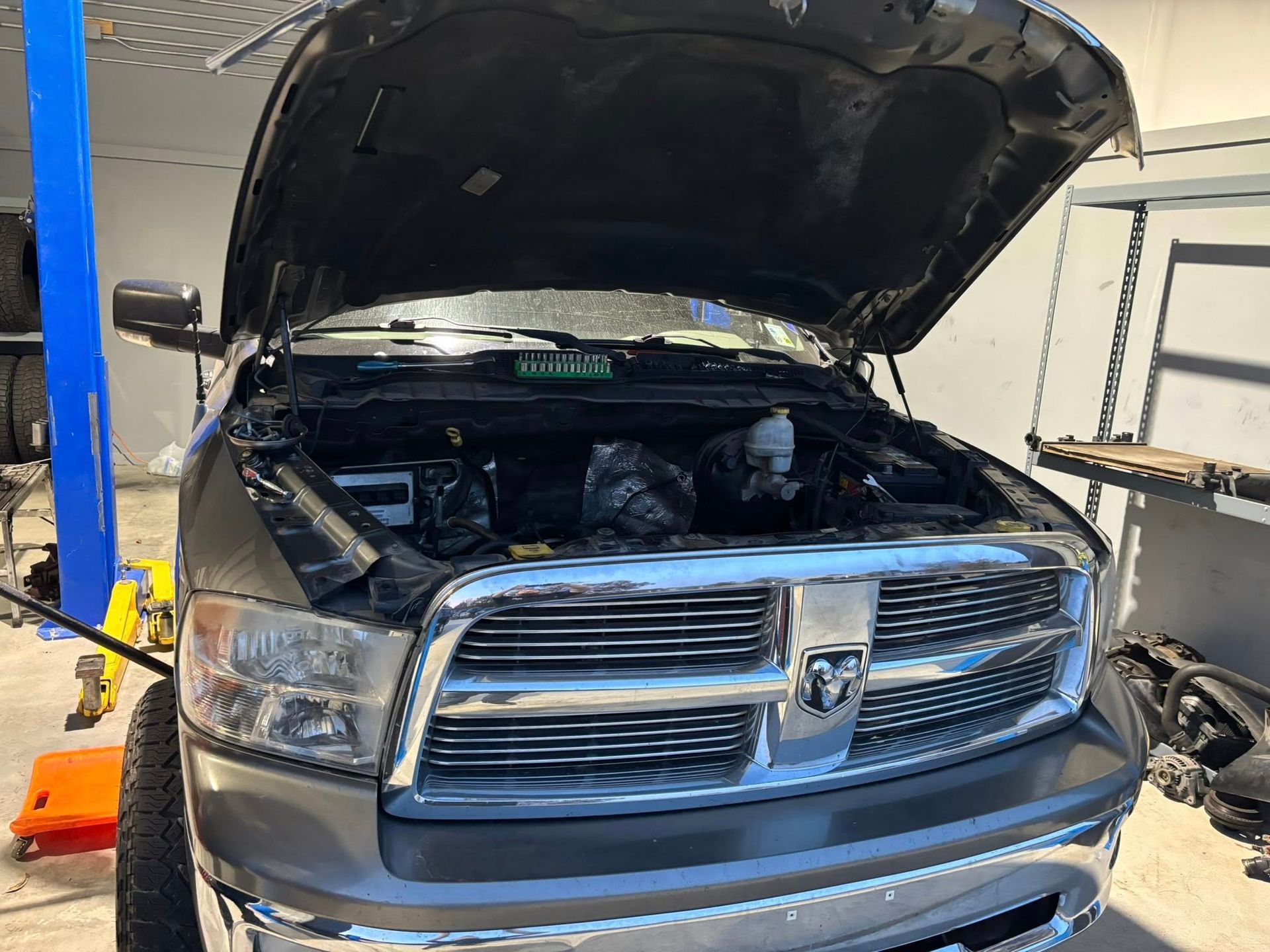 Dark gray pickup truck in a garage with its hood open for repair