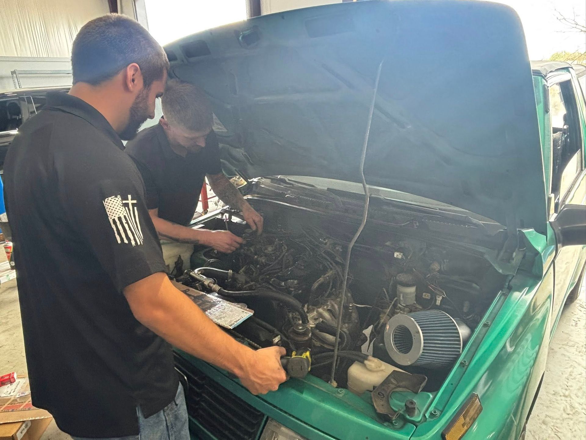 Mechanic inspecting a car engine with the hood open in a workshop