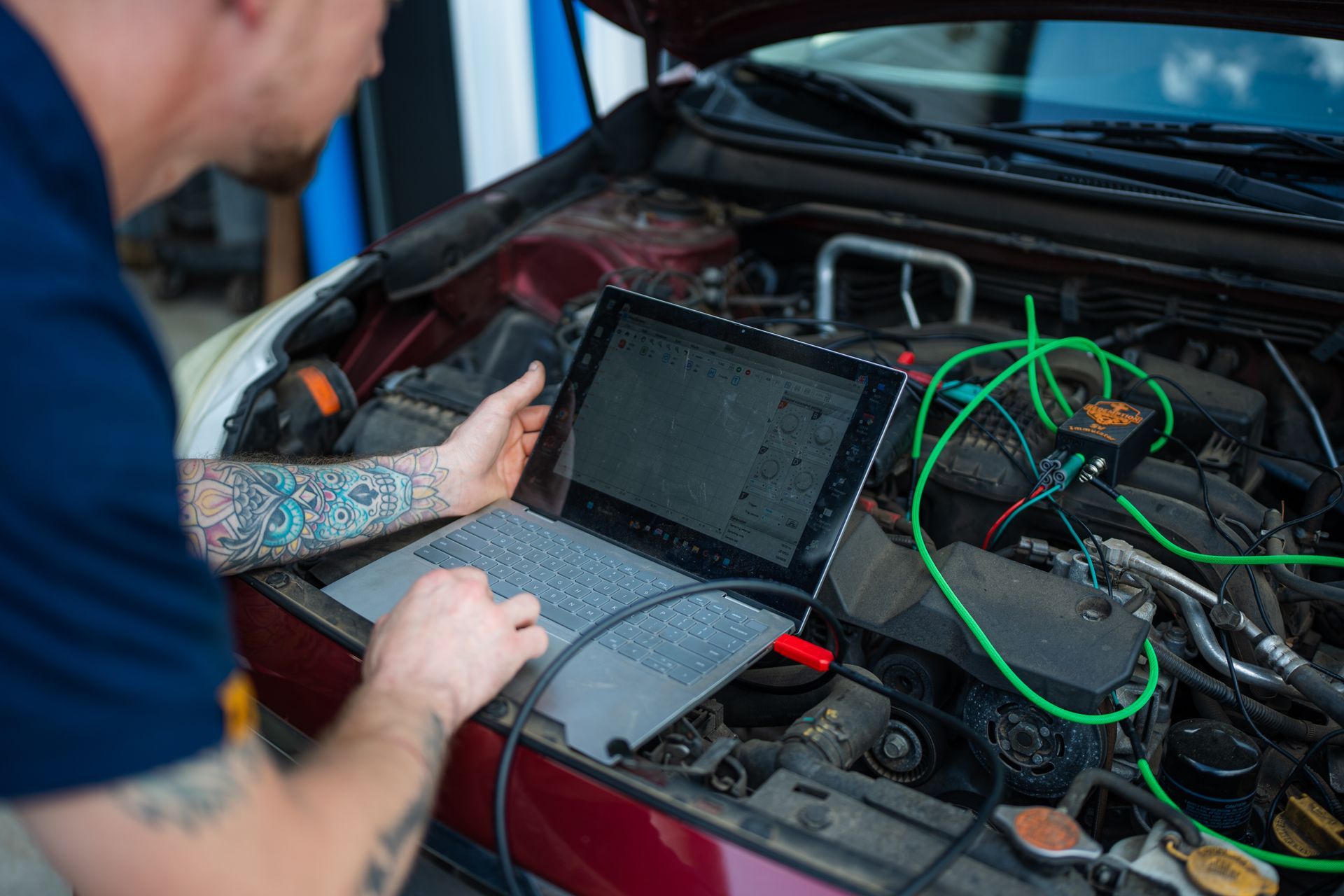 Mechanic inspecting an SUV engine bay with the hood open in a garage