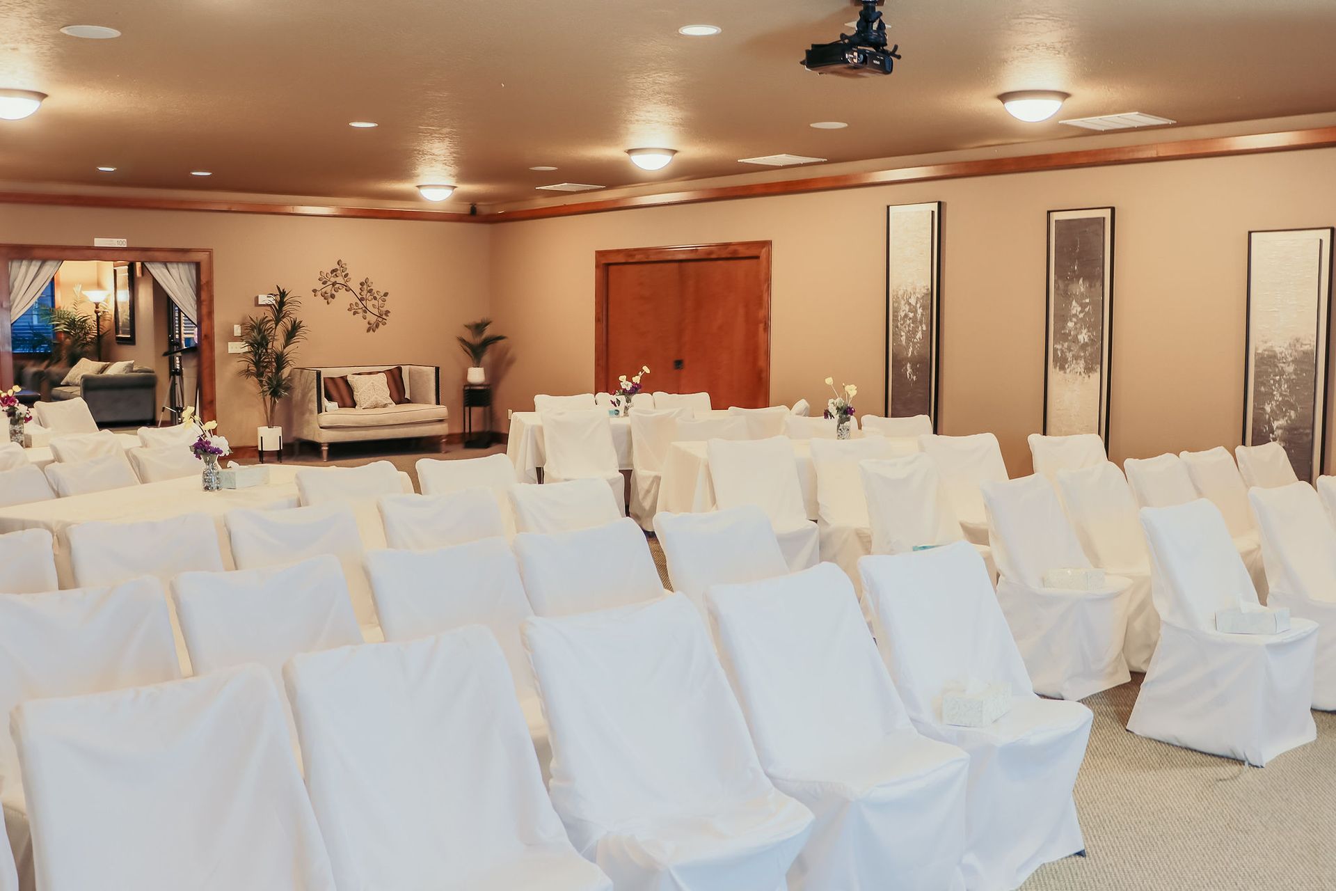 Rows of white-covered chairs arranged in a banquet hall with warm lighting
