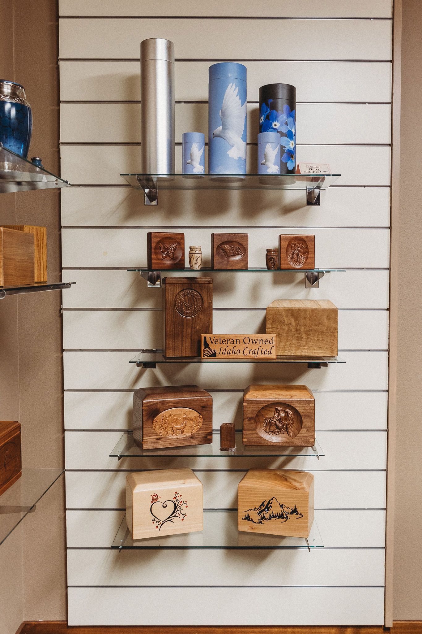 Wall display of packaged snacks and small tins on glass shelves against a white slatwall.