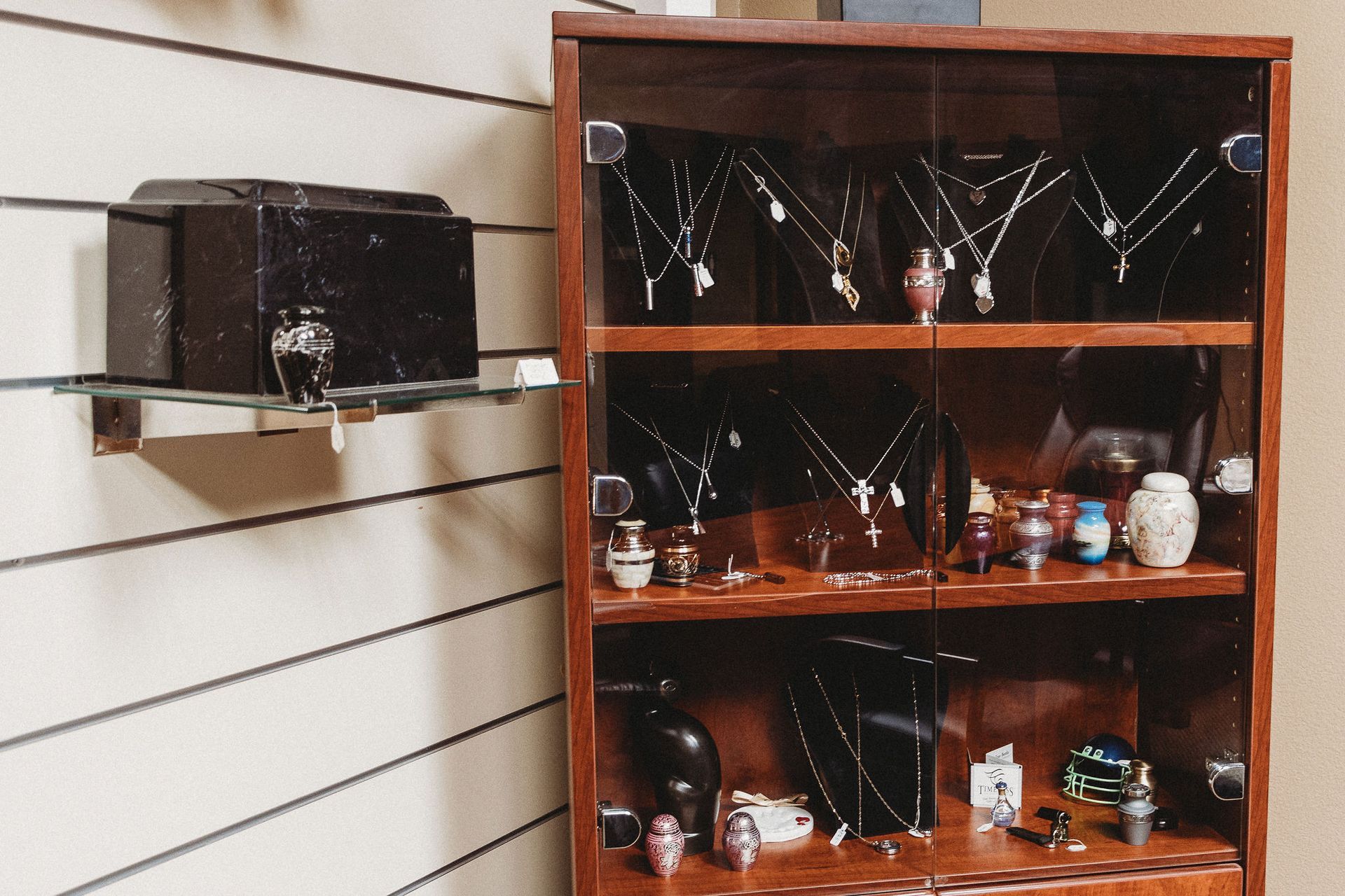 Wooden display cabinet with small decorative items in a slat-wall room