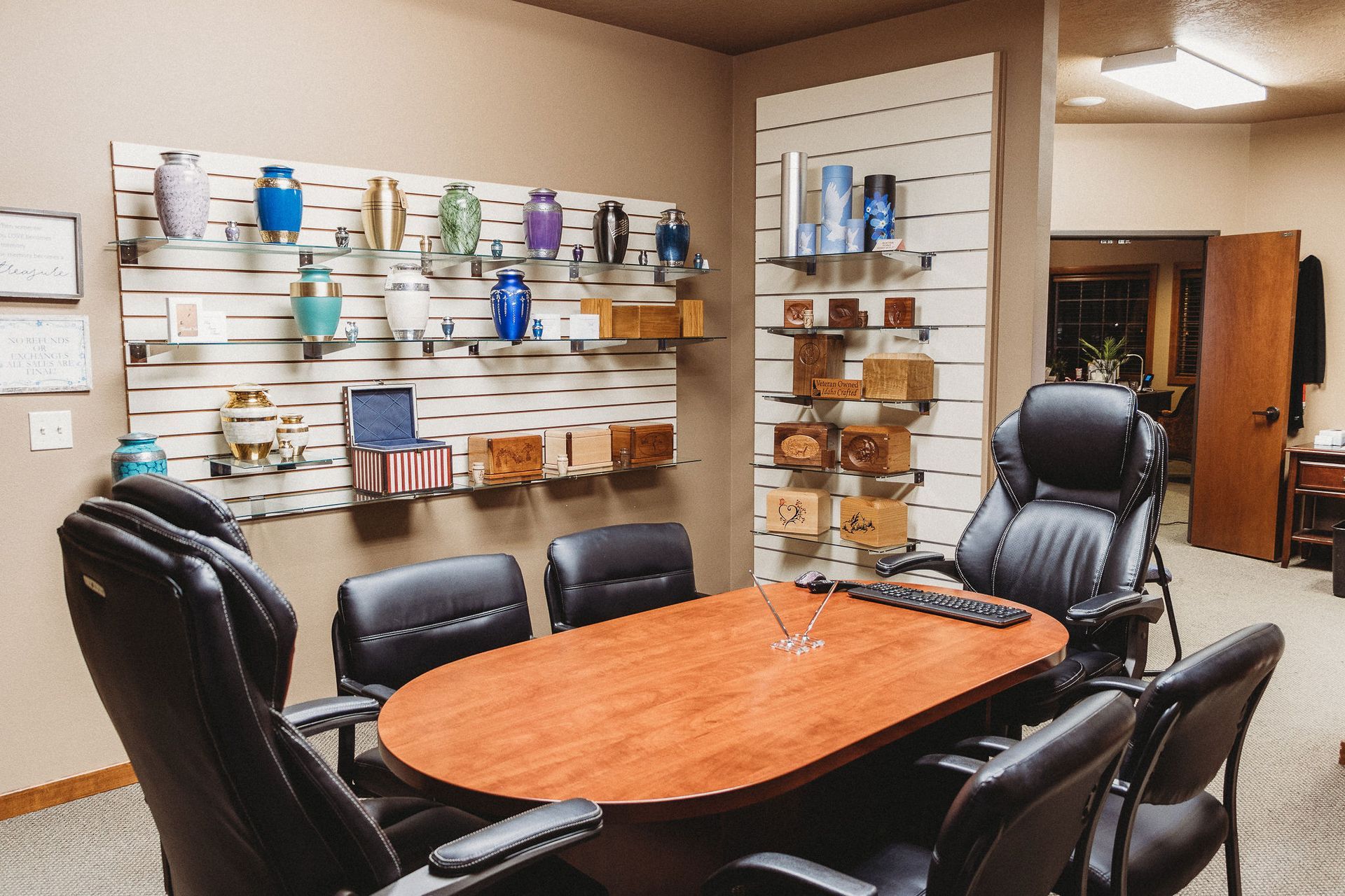 Conference room with black leather chairs, oval wooden table, and wall-mounted display shelves