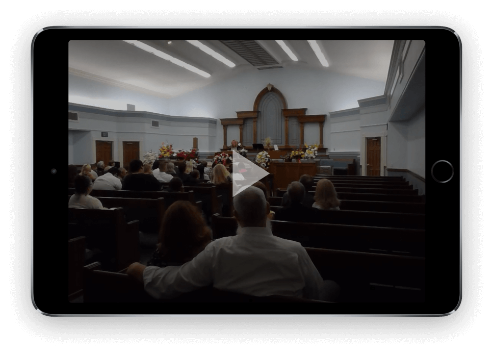 Church congregation gathered inside a sanctuary during a service, viewed from the back rows.