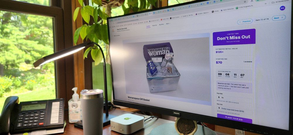 Close up of a computer screen on a desk in an office with the screen showing a Womanspace basket up for bid