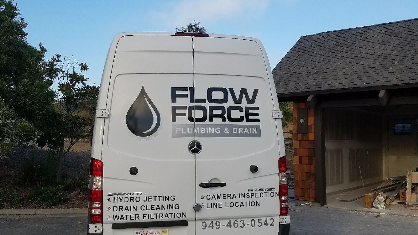 A white van with the word flow force on the back is parked in front of a house.