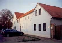 Ein weißes Gebäude mit einem roten Dach und einem davor geparkten schwarzen Auto.