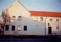Ein weißes Gebäude mit einem roten Dach und einem Baum davor.