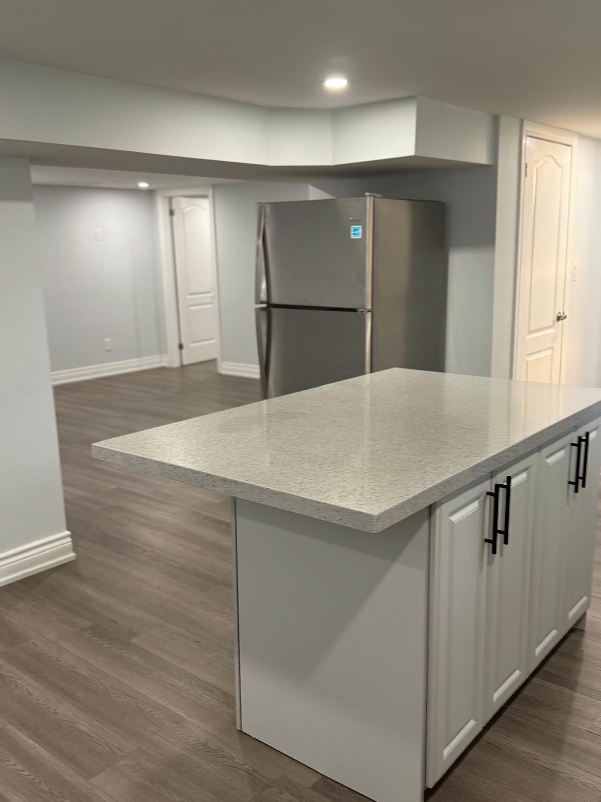 A kitchen with a large island and a refrigerator.