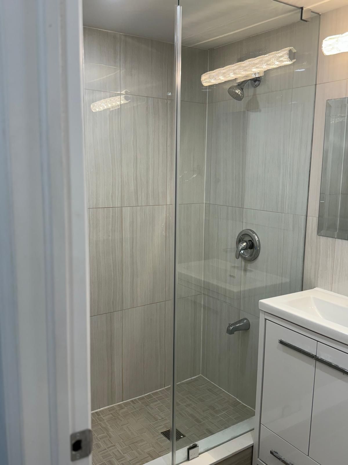 A bathroom with a walk in shower and a sink.