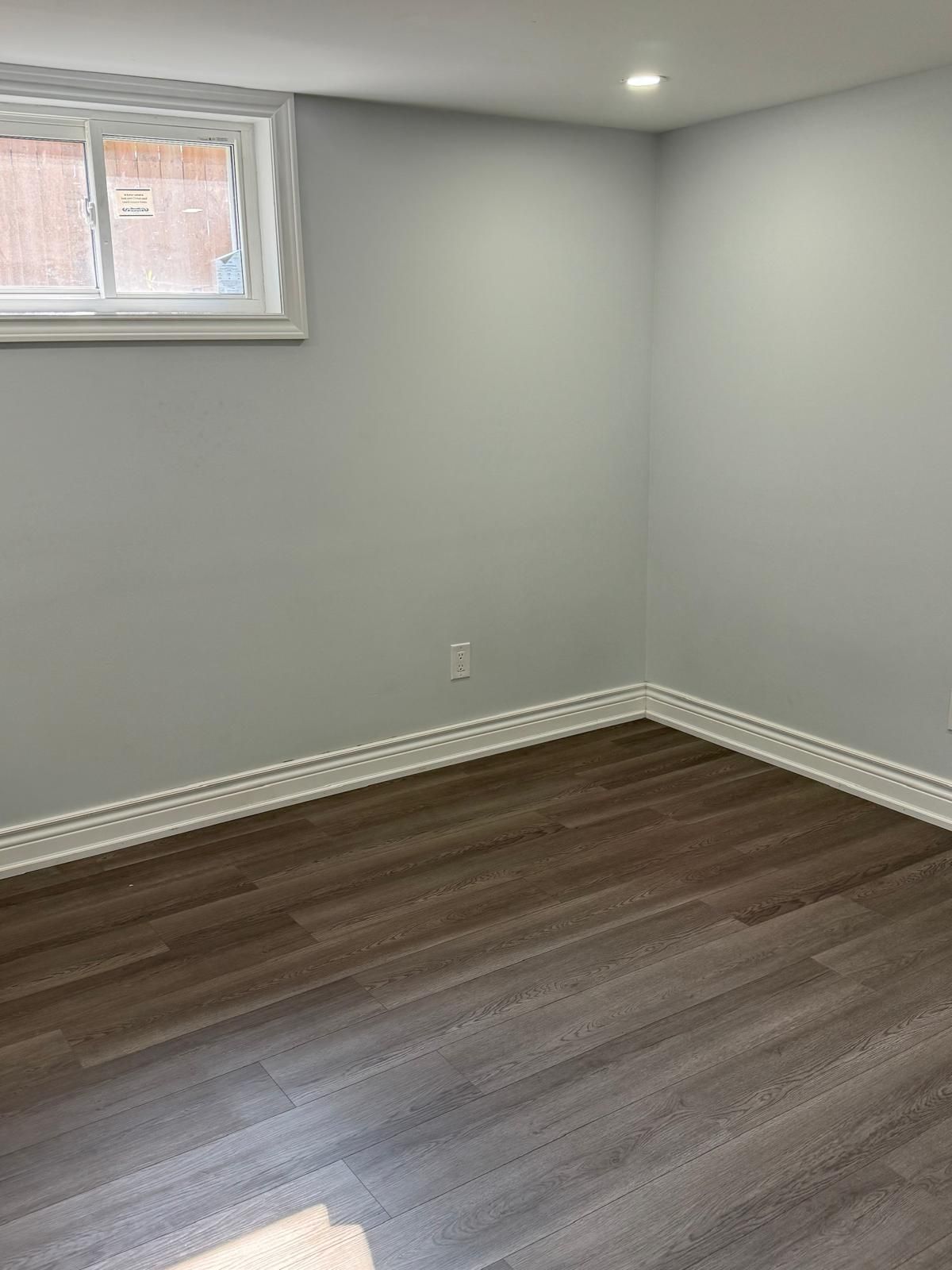 An empty room with hardwood floors and a window.
