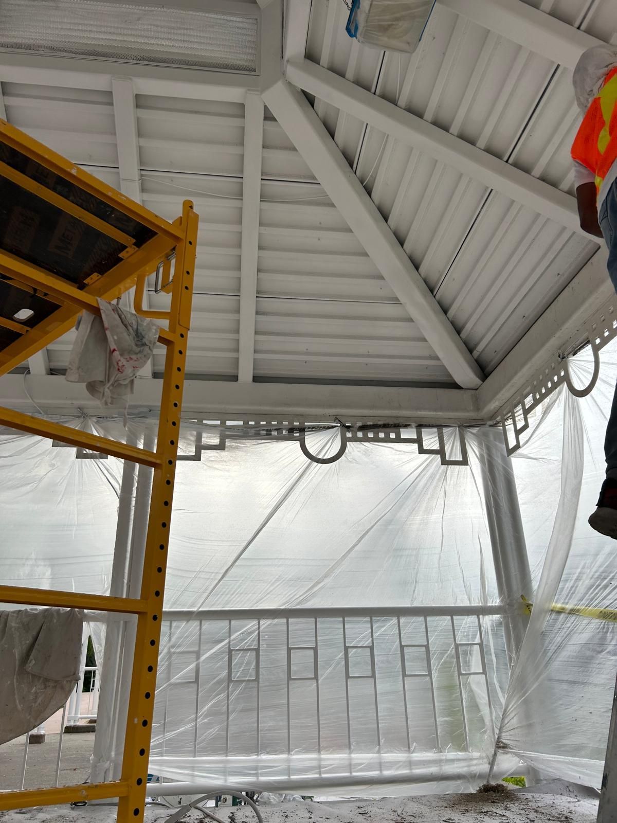 A man is painting the ceiling of a gazebo