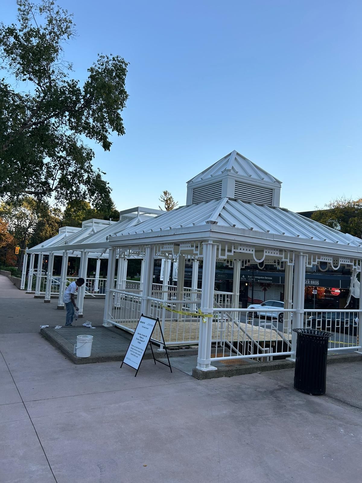 A white gazebo with a metal roof is being built in a park.
