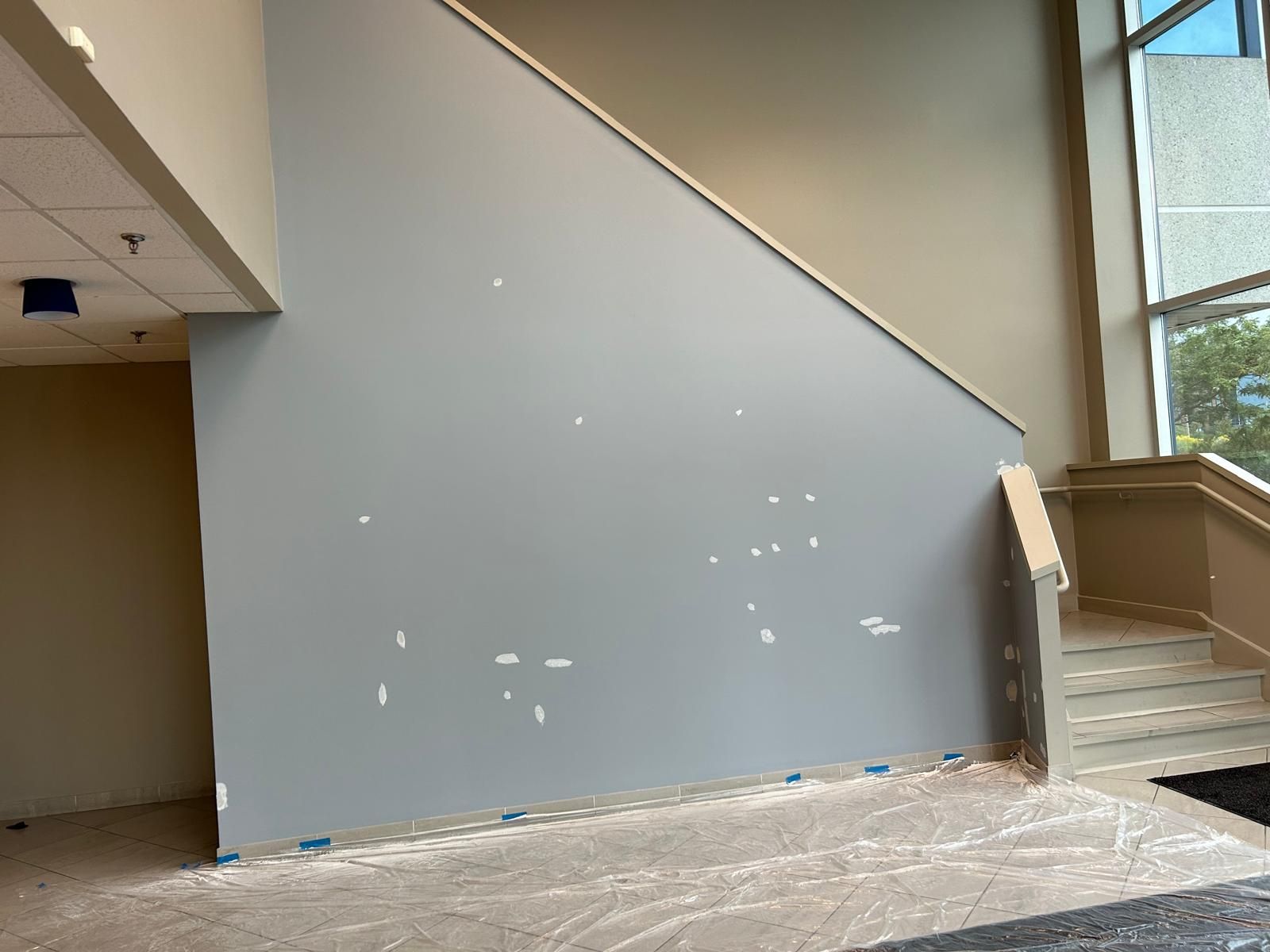A room with stairs and a wall that is being painted.