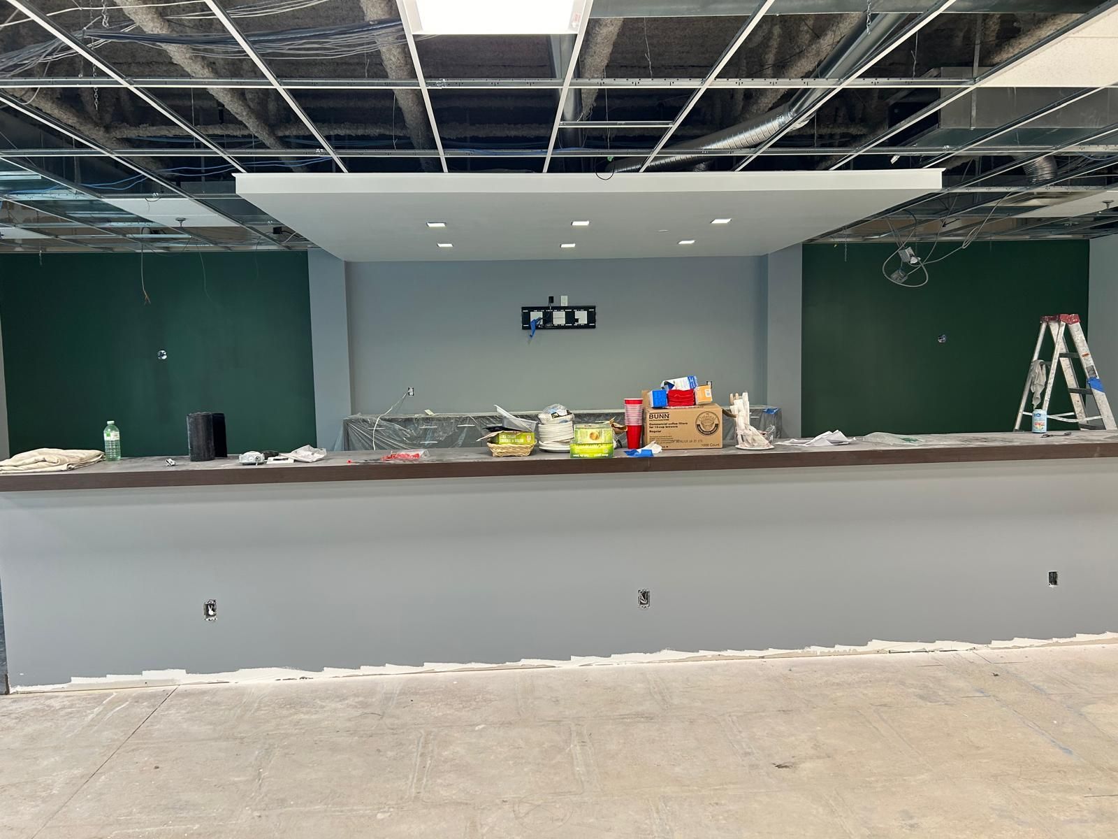 A large empty room with a bar and a ladder.
