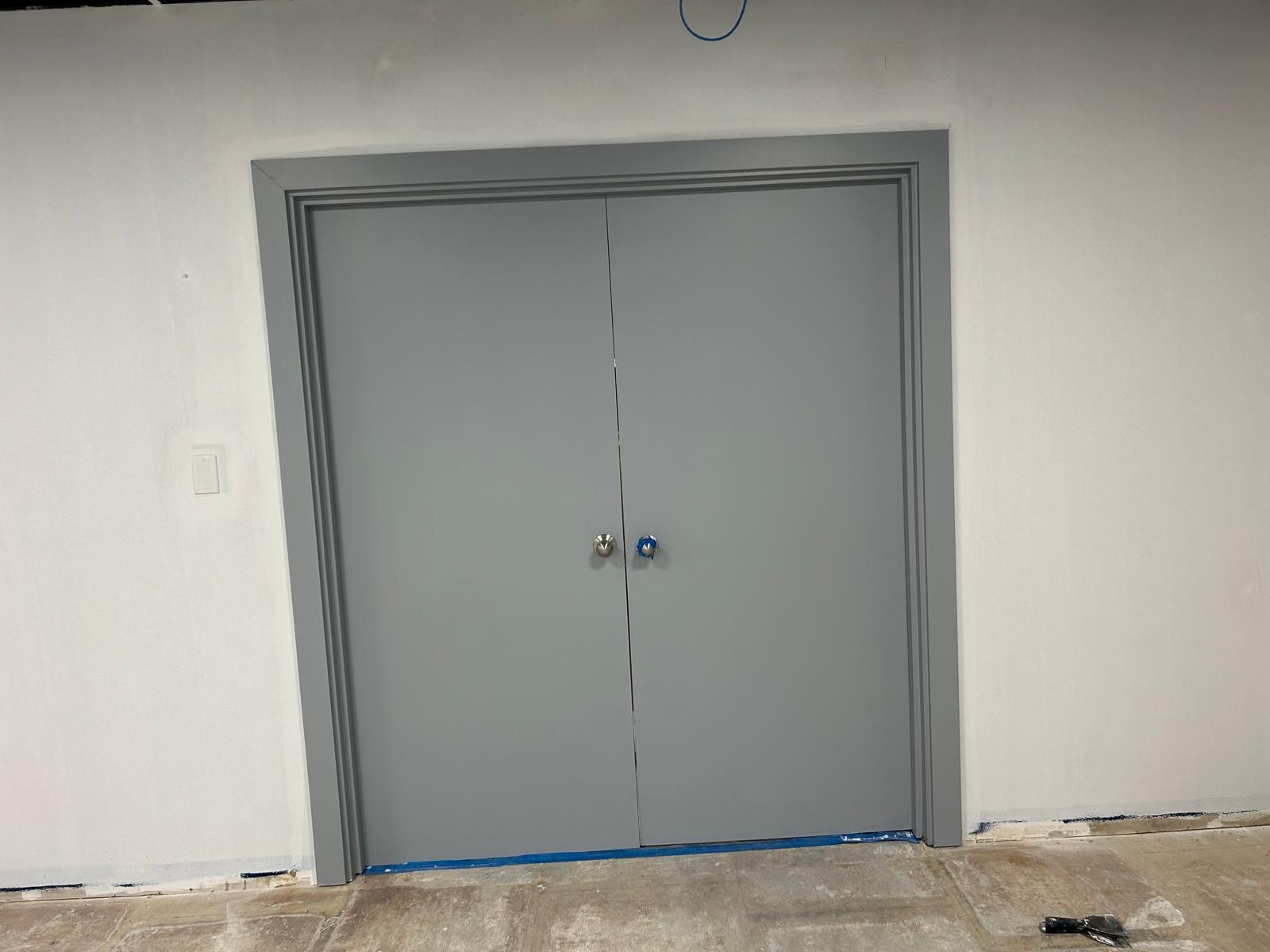 A gray door is sitting in a room next to a white wall.