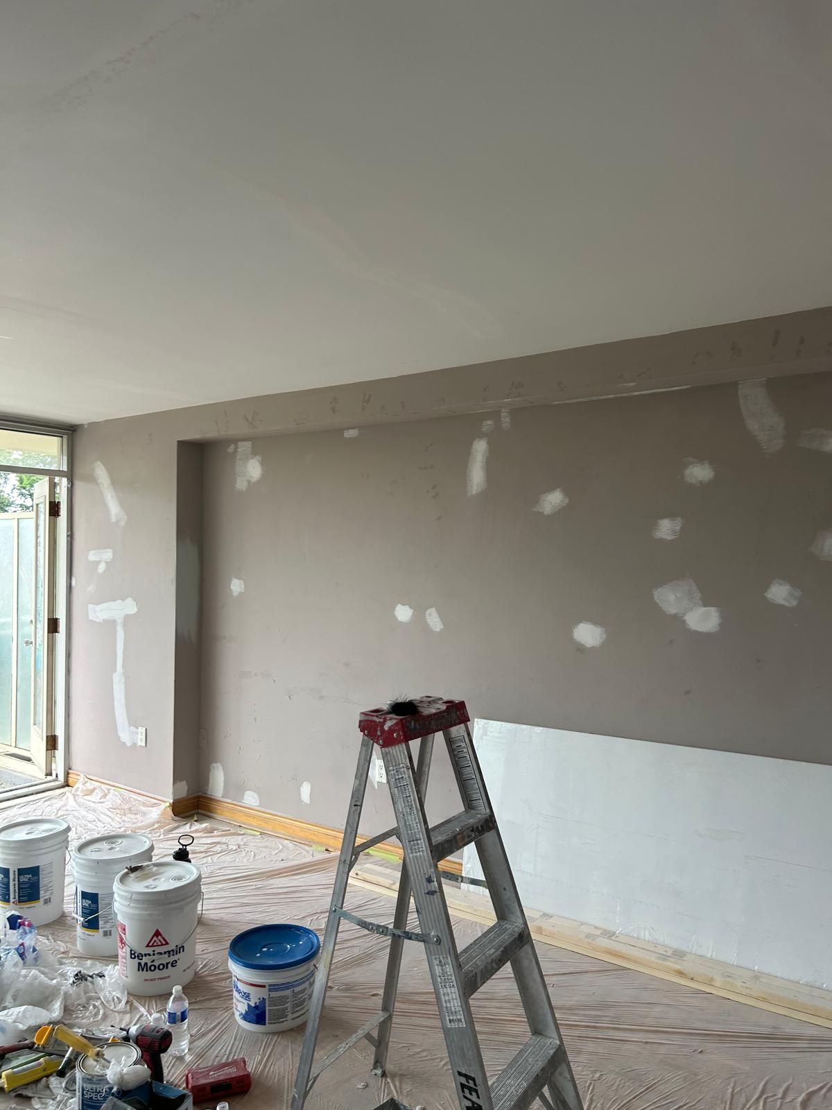 A room is being painted with buckets of paint and a ladder.