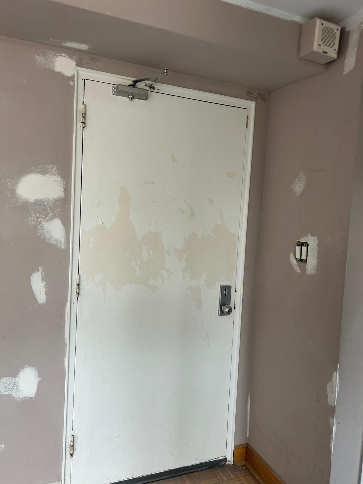 A white door is sitting in a room next to a wall.