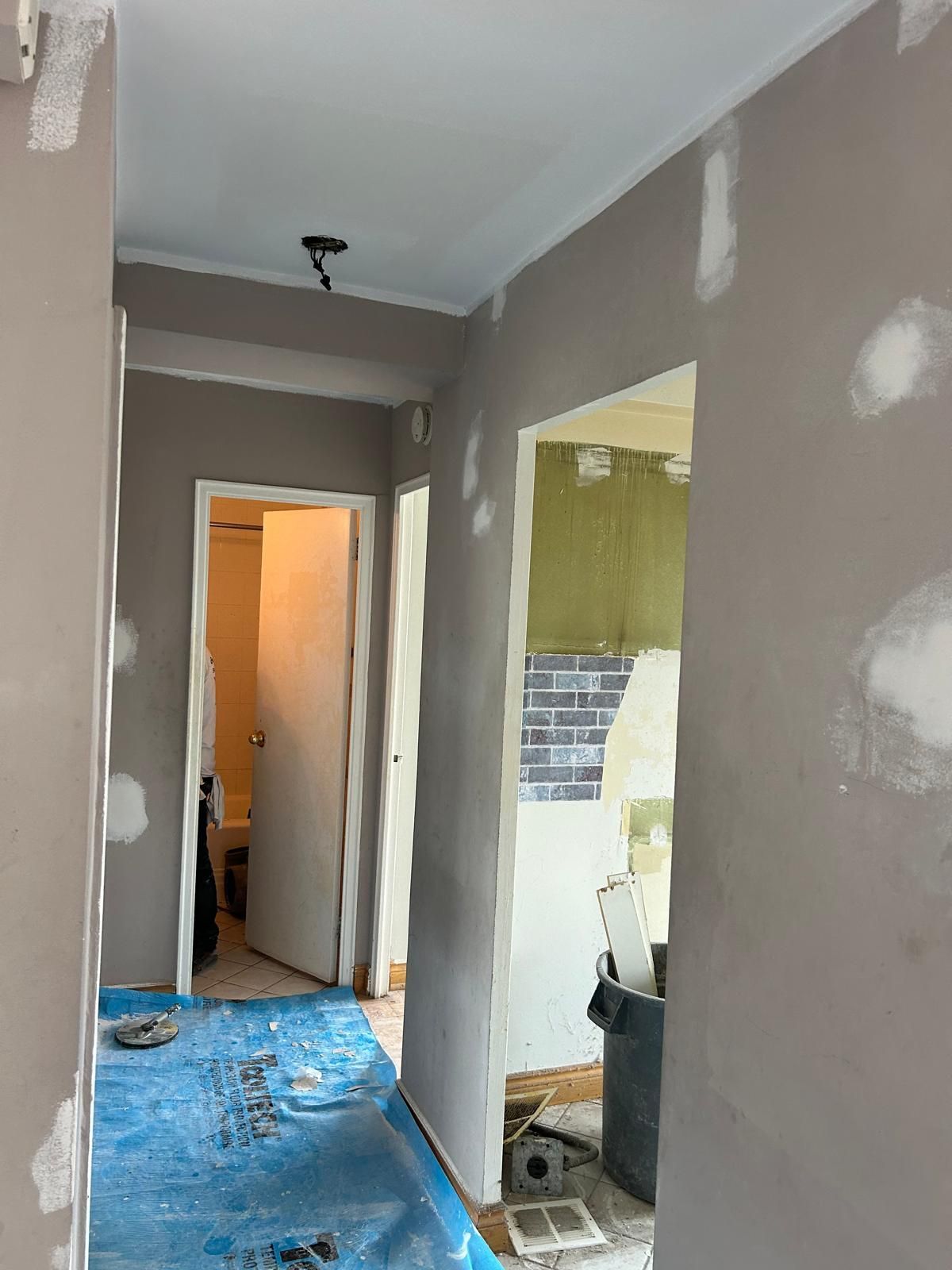 A hallway in a house under construction with a blue tarp on the floor.