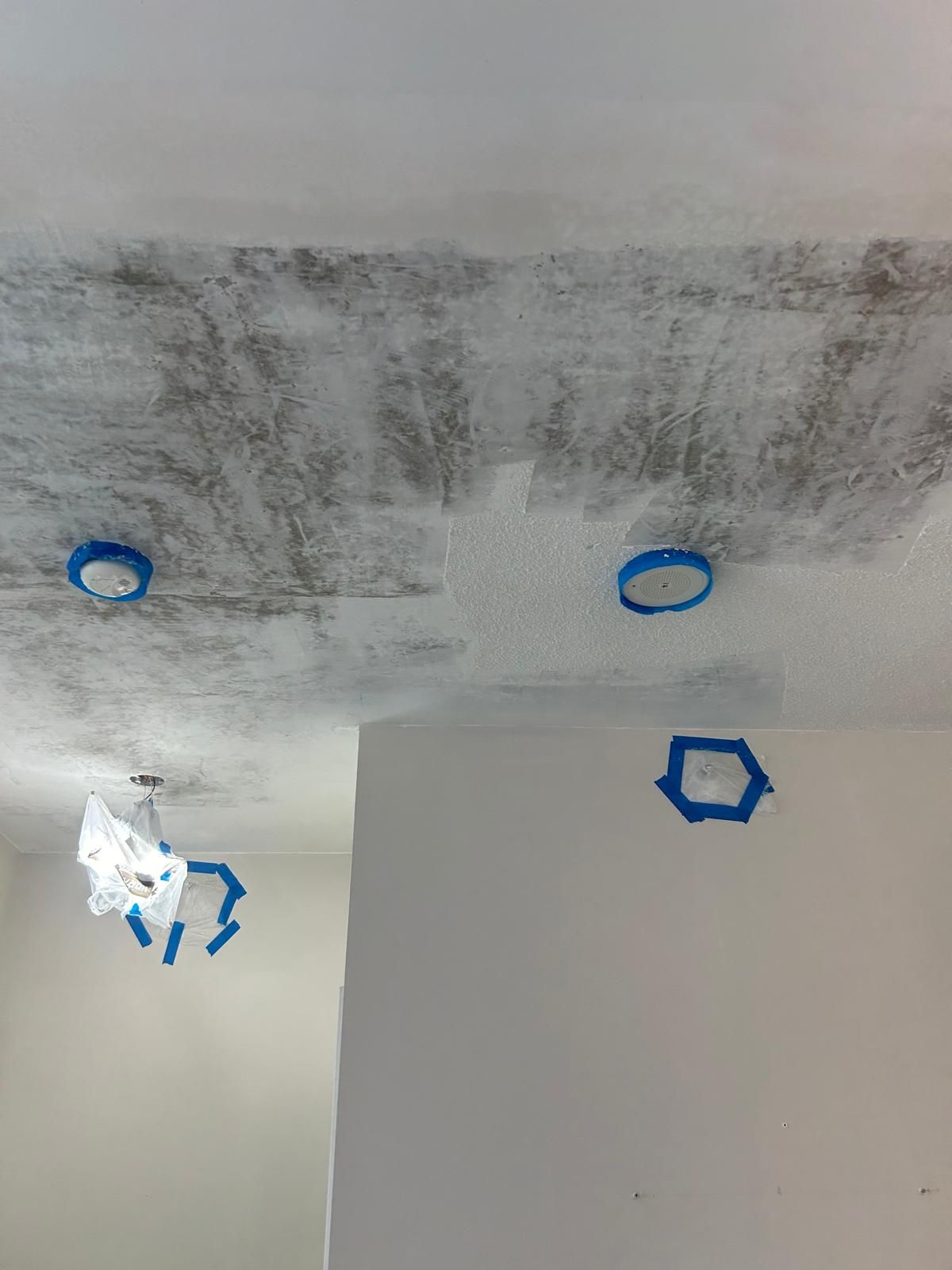 A ceiling with holes in it and blue tape on it.