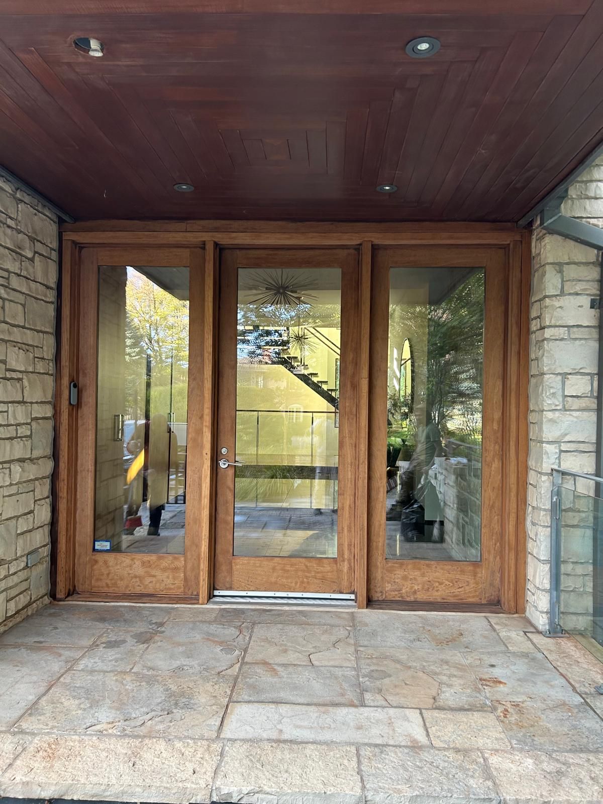 The front door of a house with a wooden frame and glass doors.